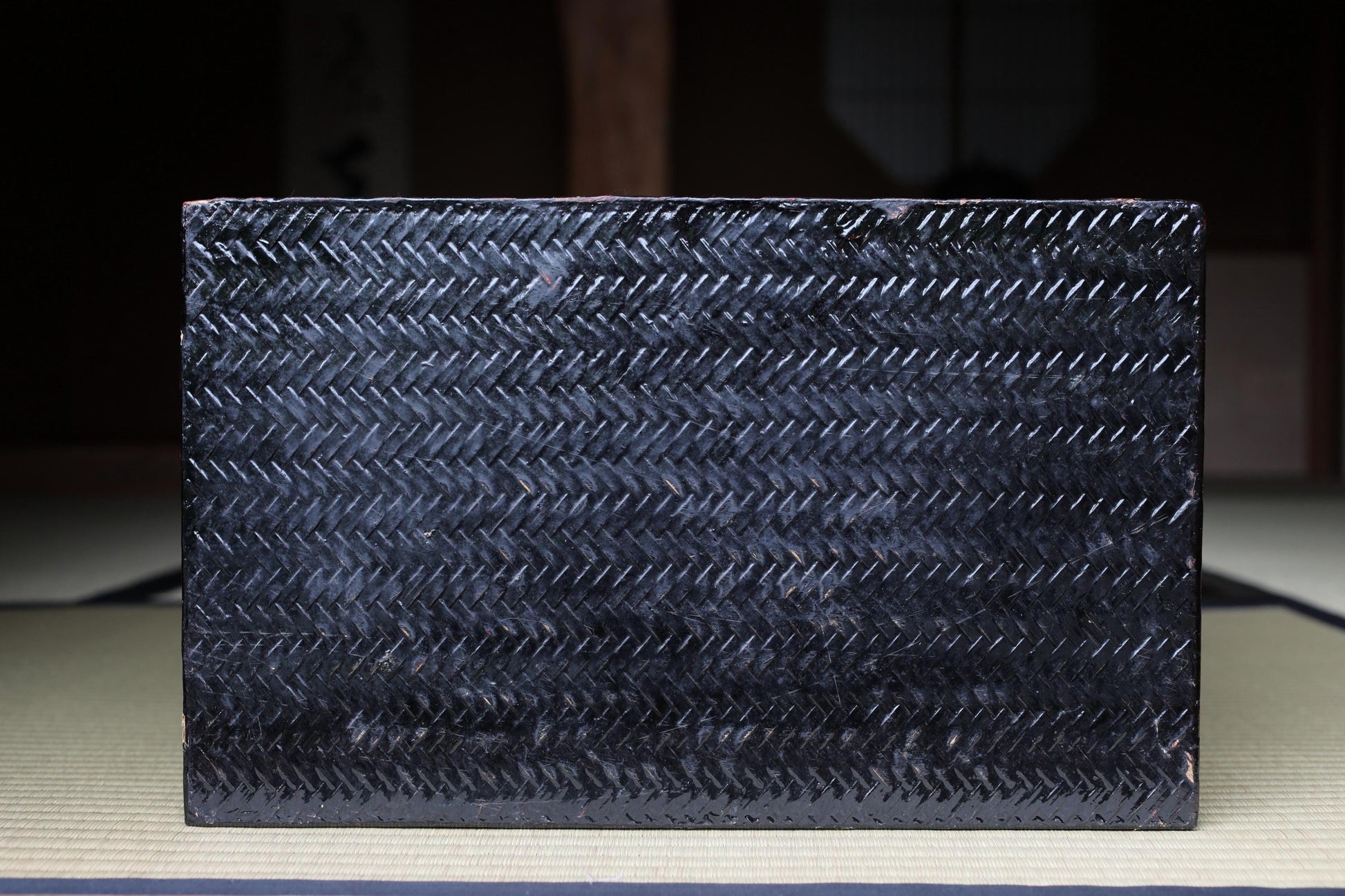 A dark, textured surface with a zigzag pattern, possibly a piece of furniture or a decorative item.