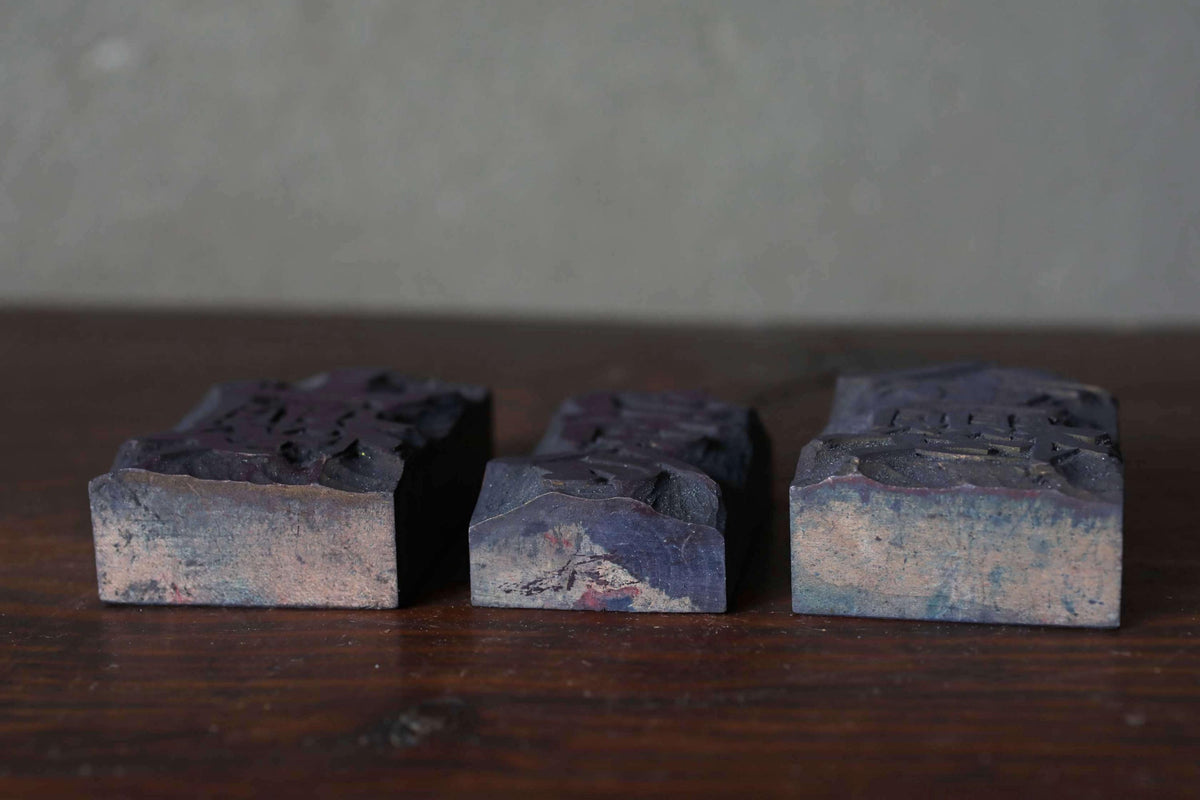 Three dark-colored wooden blocks or blocks of wood are arranged on a wooden surface.