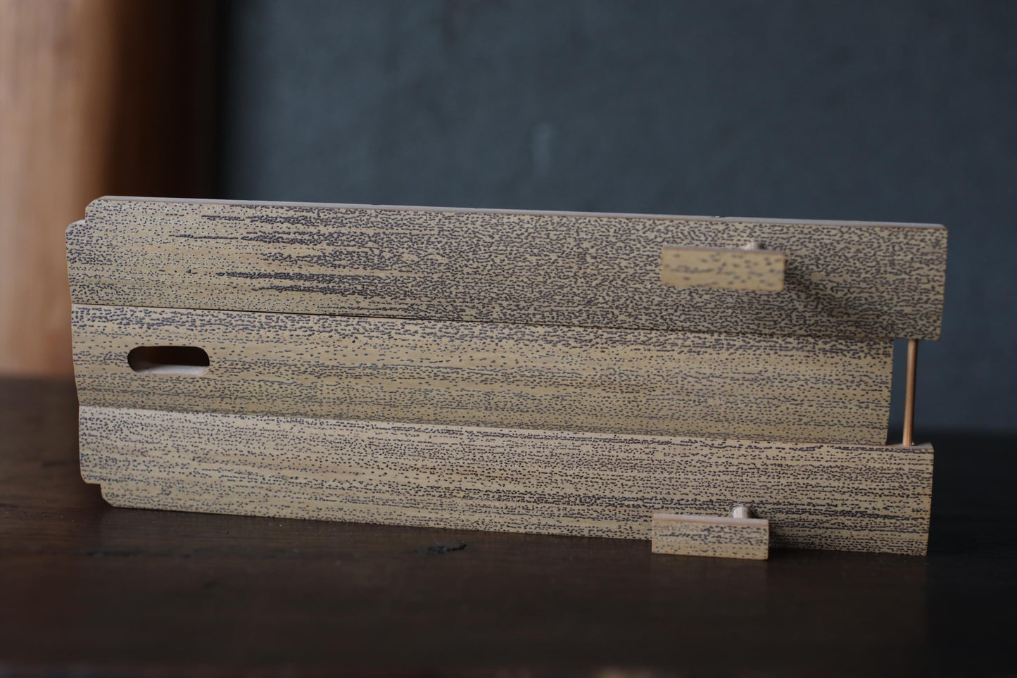 a wooden object with a textured surface, sitting on a dark surface.