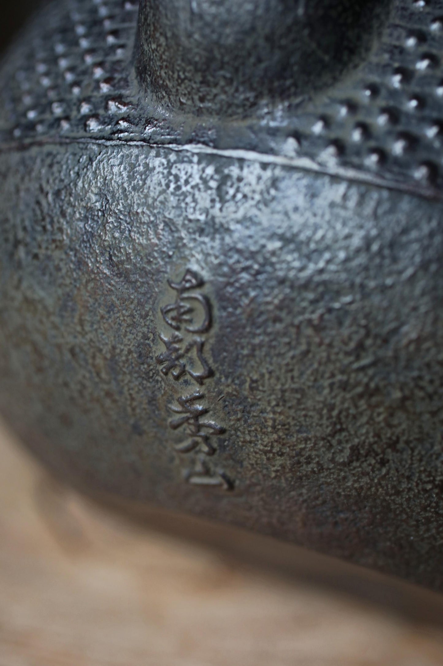 A close-up image of a metal object with a textured surface, possibly a piece of pottery or a sculpture.