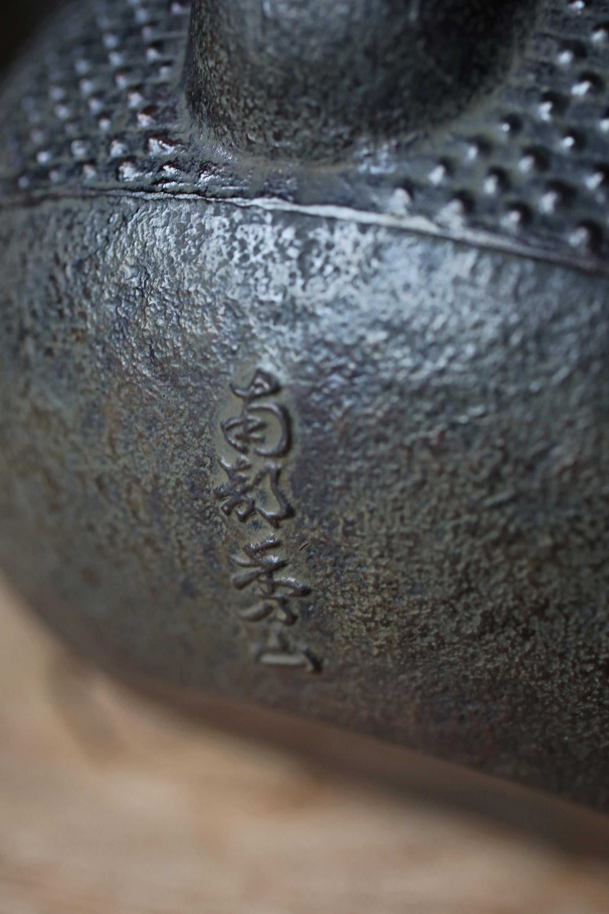 A close-up image of a metal object with a textured surface, possibly a piece of pottery or a sculpture.