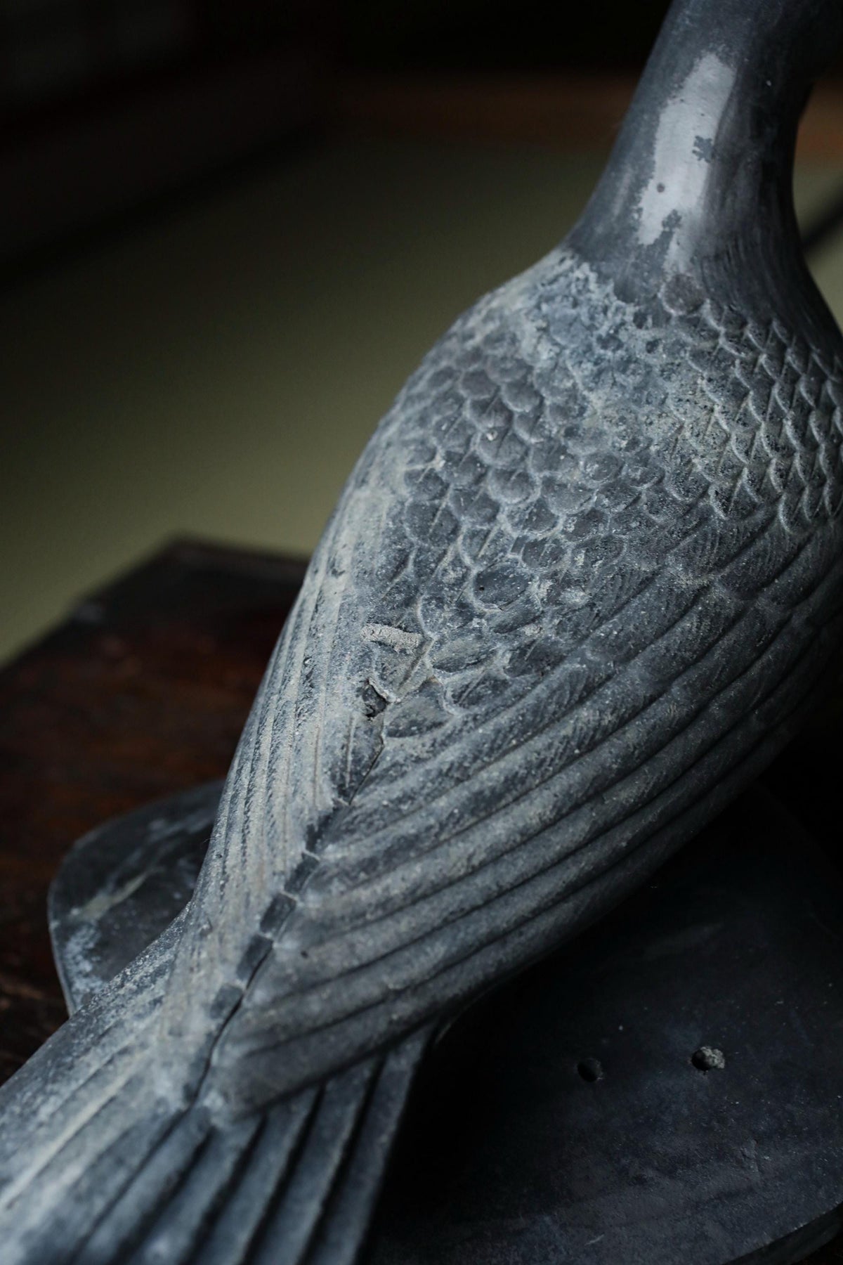 A close-up view of a metal sculpture of a bird, with intricate details and a textured surface.