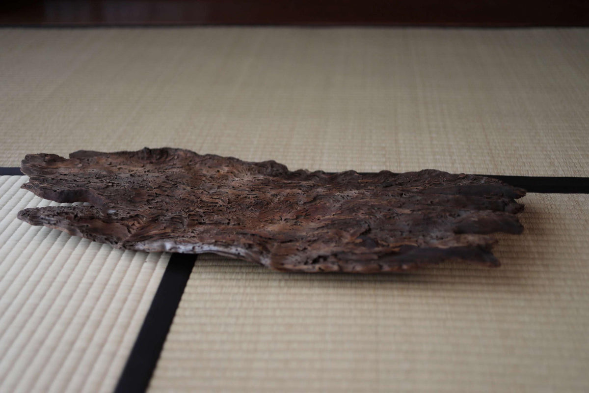 a piece of driftwood or drift stone resting on a white mat or tatami mat, creating a rustic and natural aesthetic.