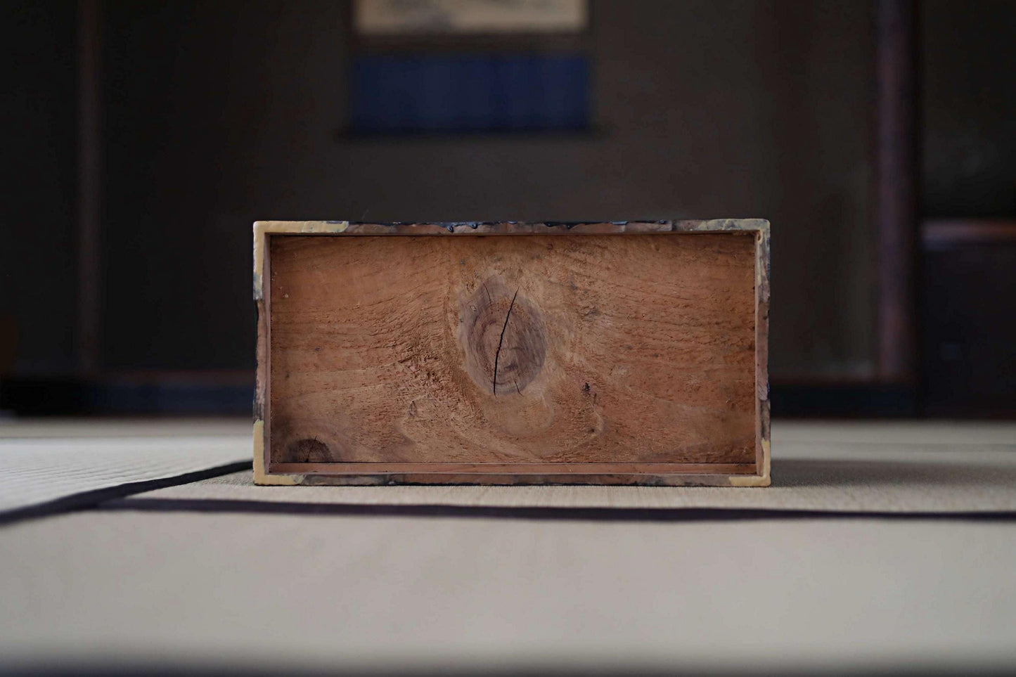 A wooden box with a visible wood grain texture sits on a white surface.