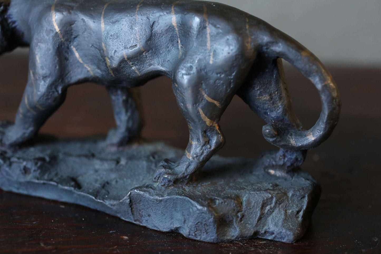 A close-up view of a dark-colored metal sculpture depicting a walking animal, possibly a panther or a similar feline creature.