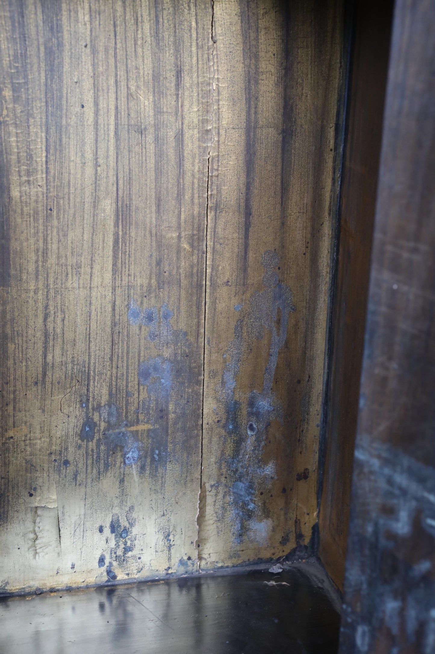 a close-up view of a wooden surface with visible signs of wear and tear, including peeling paint and some areas of discoloration.