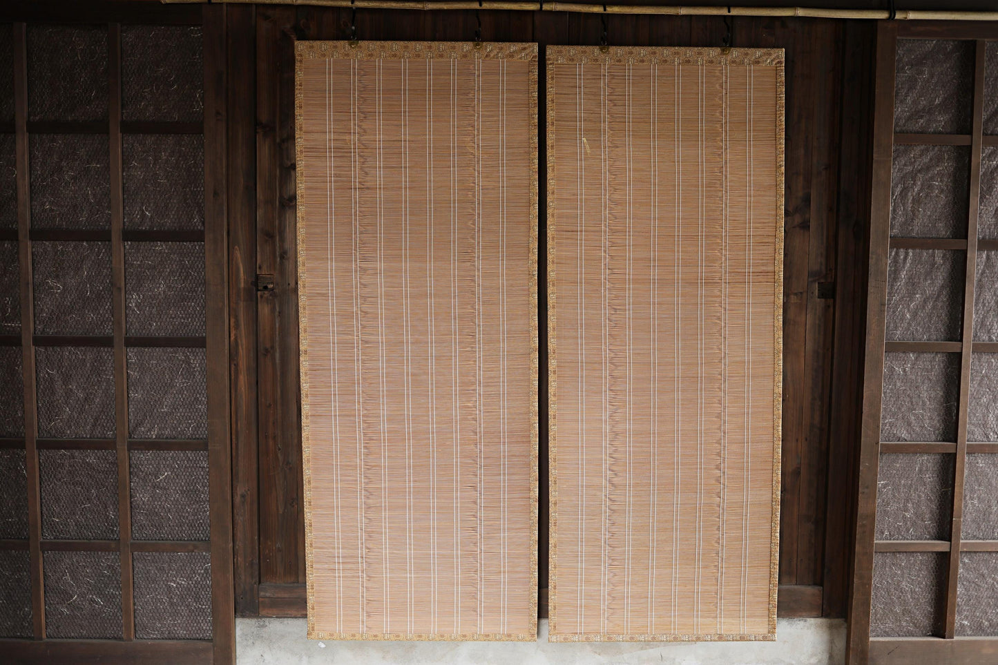 a pair of wooden doors with bamboo blinds, set in a wooden frame. The blinds are made of bamboo and have a traditional Japanese appearance.
