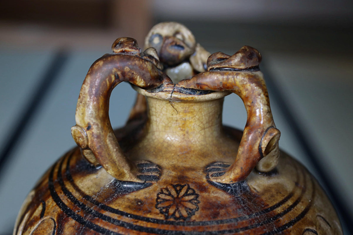 A close-up image of a ceramic vase with intricate designs and patterns, featuring two handles and a central floral motif.