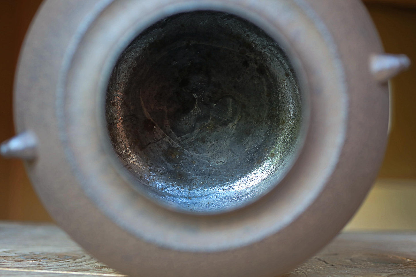 the inside of a metal container, with a dark, rusty-looking surface visible through the opening.
