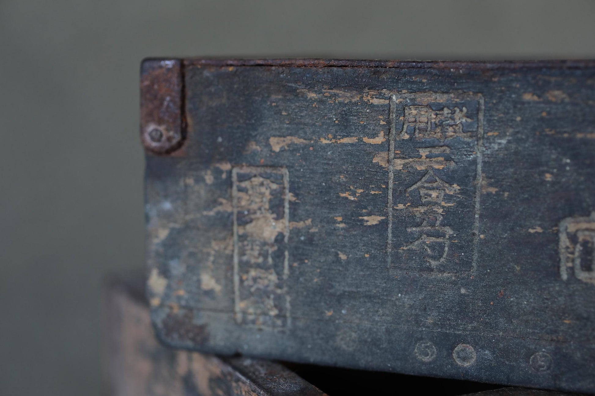 a close-up view of a weathered, rusted metal surface with some text or symbols in a foreign language.