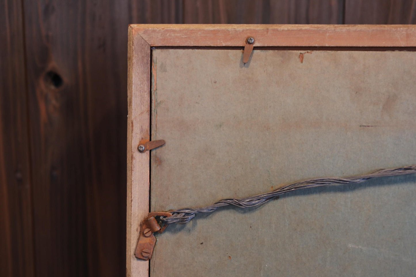 a close-up view of a wooden frame with a wire attached to it, against a wooden background.