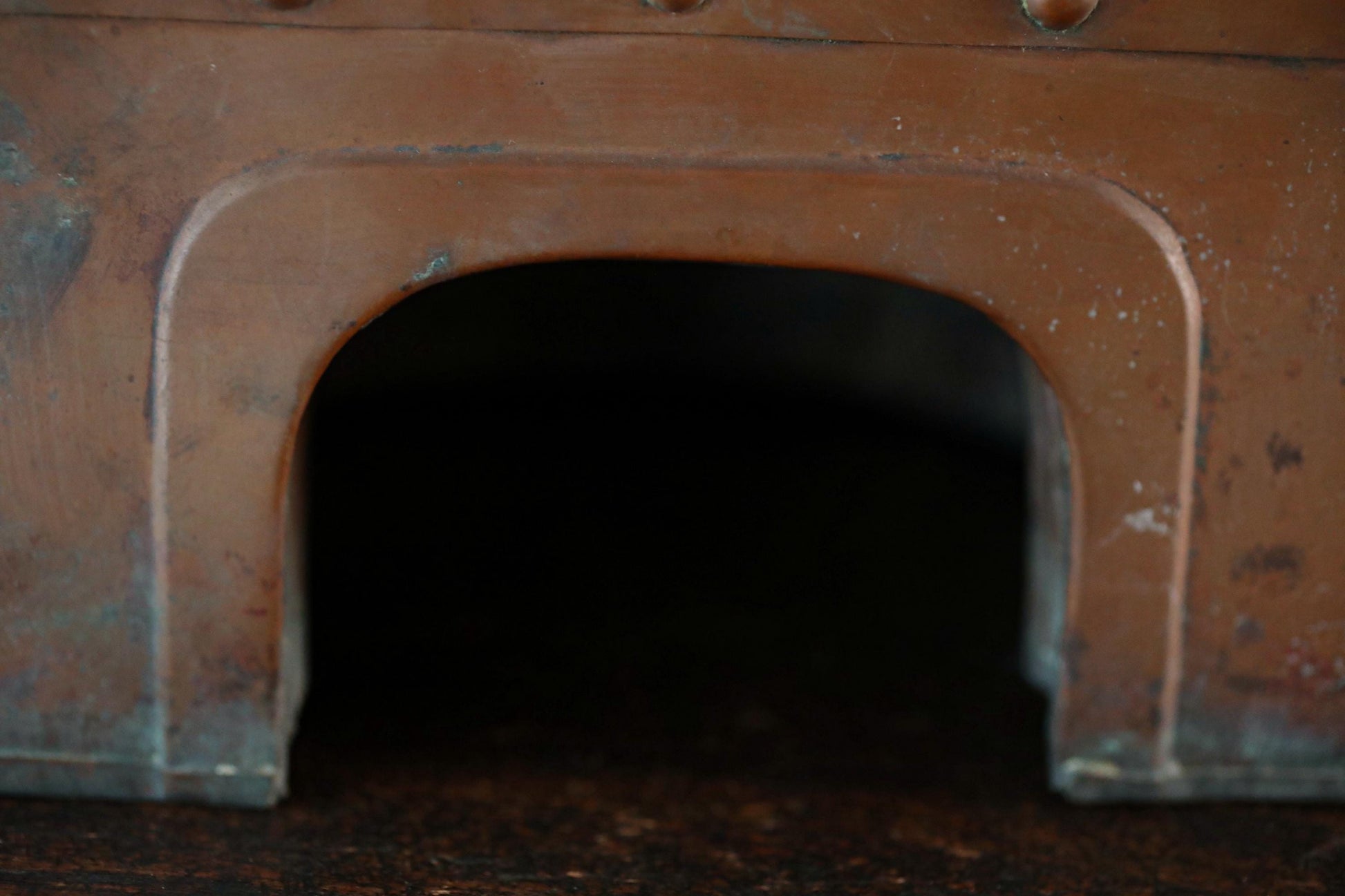 a close-up view of a dark, arched opening or doorway, with a reddish-brown hue.