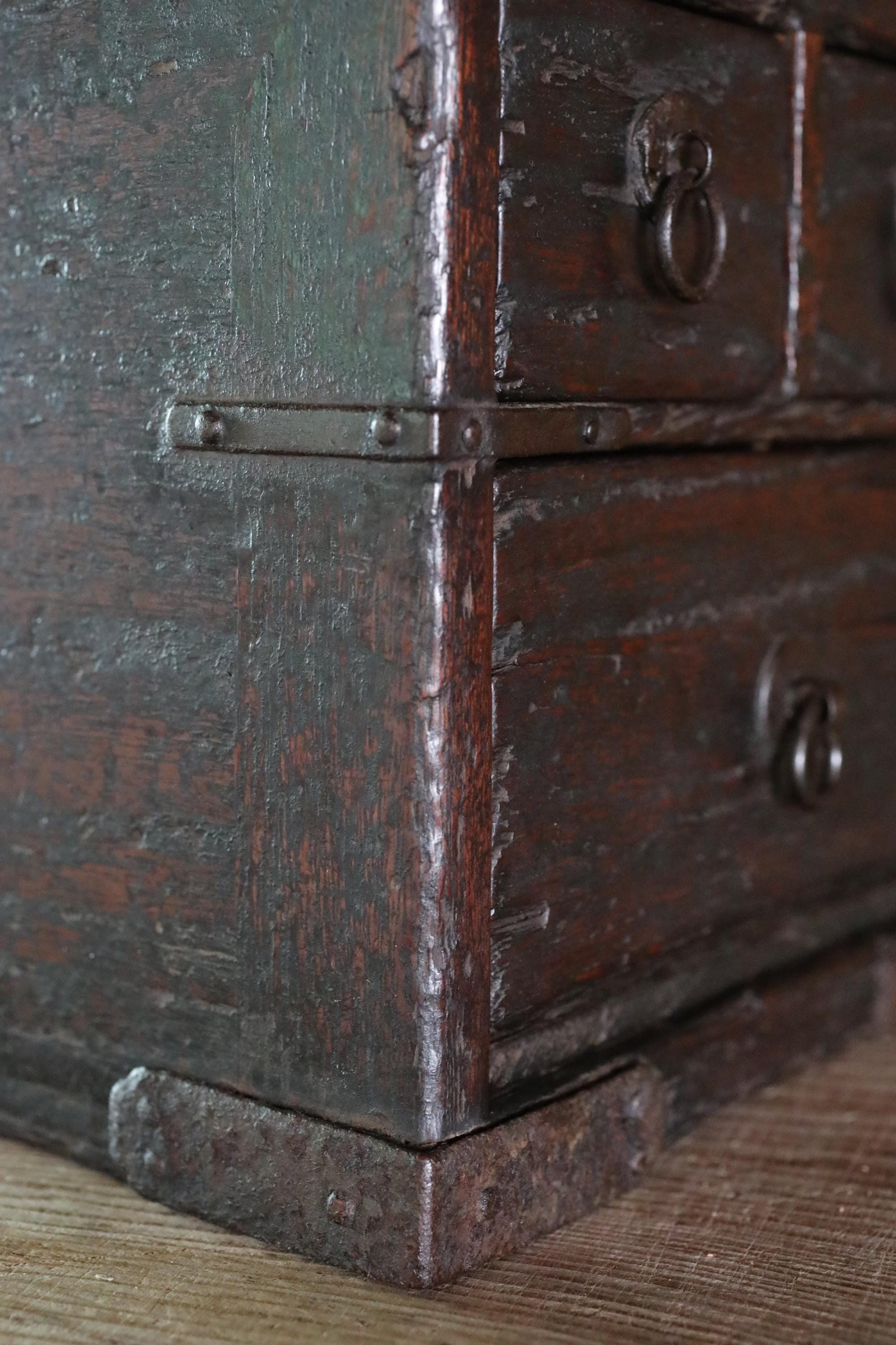 a close-up view of a wooden chest with metal hardware, including a lock and handles, resting on a wooden surface.
