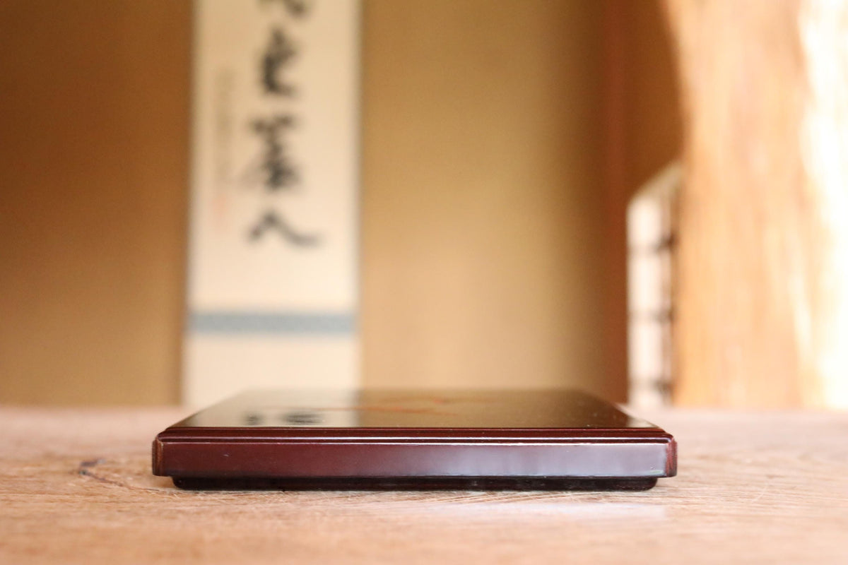 A wooden surface with a dark-colored object, possibly a piece of furniture or a decorative item, placed on it.