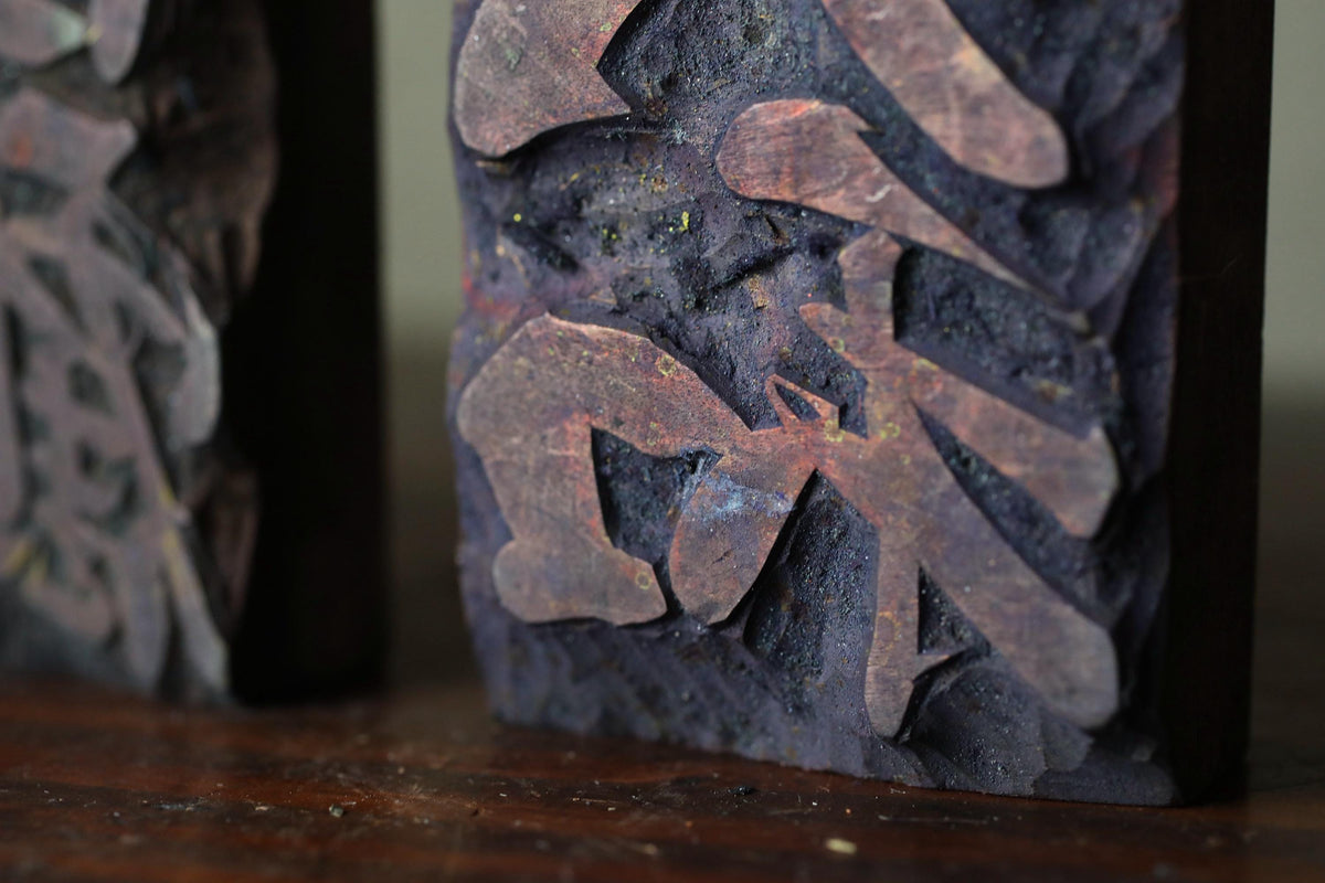 a close-up view of a dark-colored, textured surface with a pattern of shapes and lines, possibly resembling a carved or sculpted piece of art.