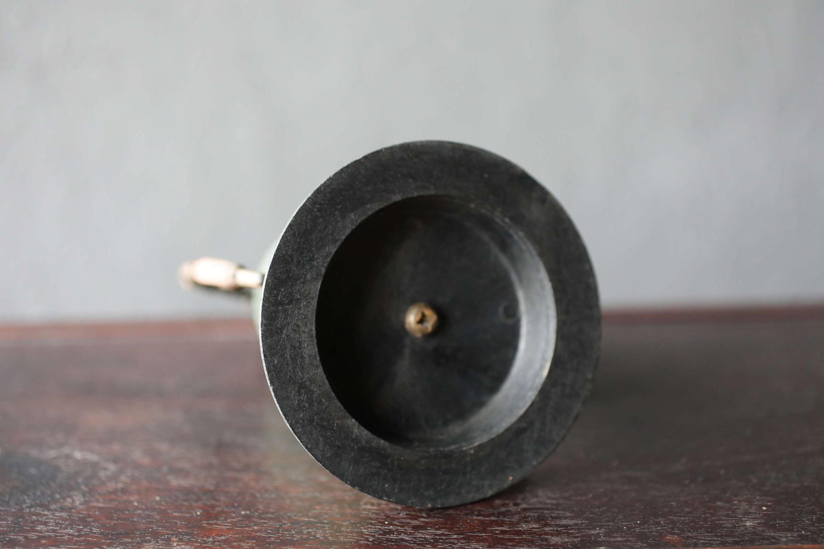 A black, round object with a small hole in the center, placed on a wooden surface against a gray background.
