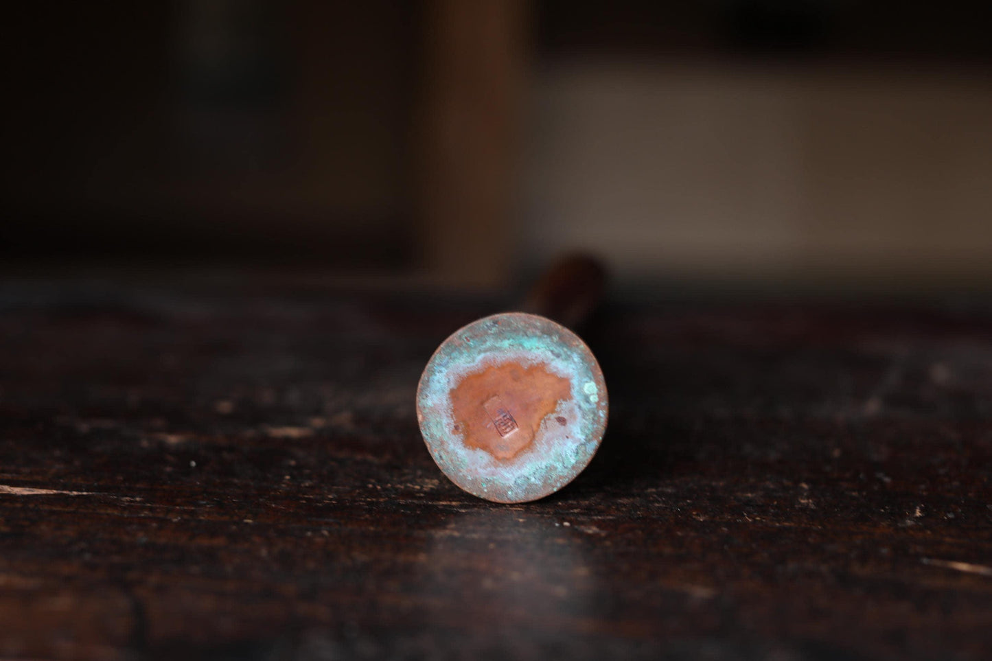 A rusted metal object with a circular hole in the center, resting on a dark wooden surface.