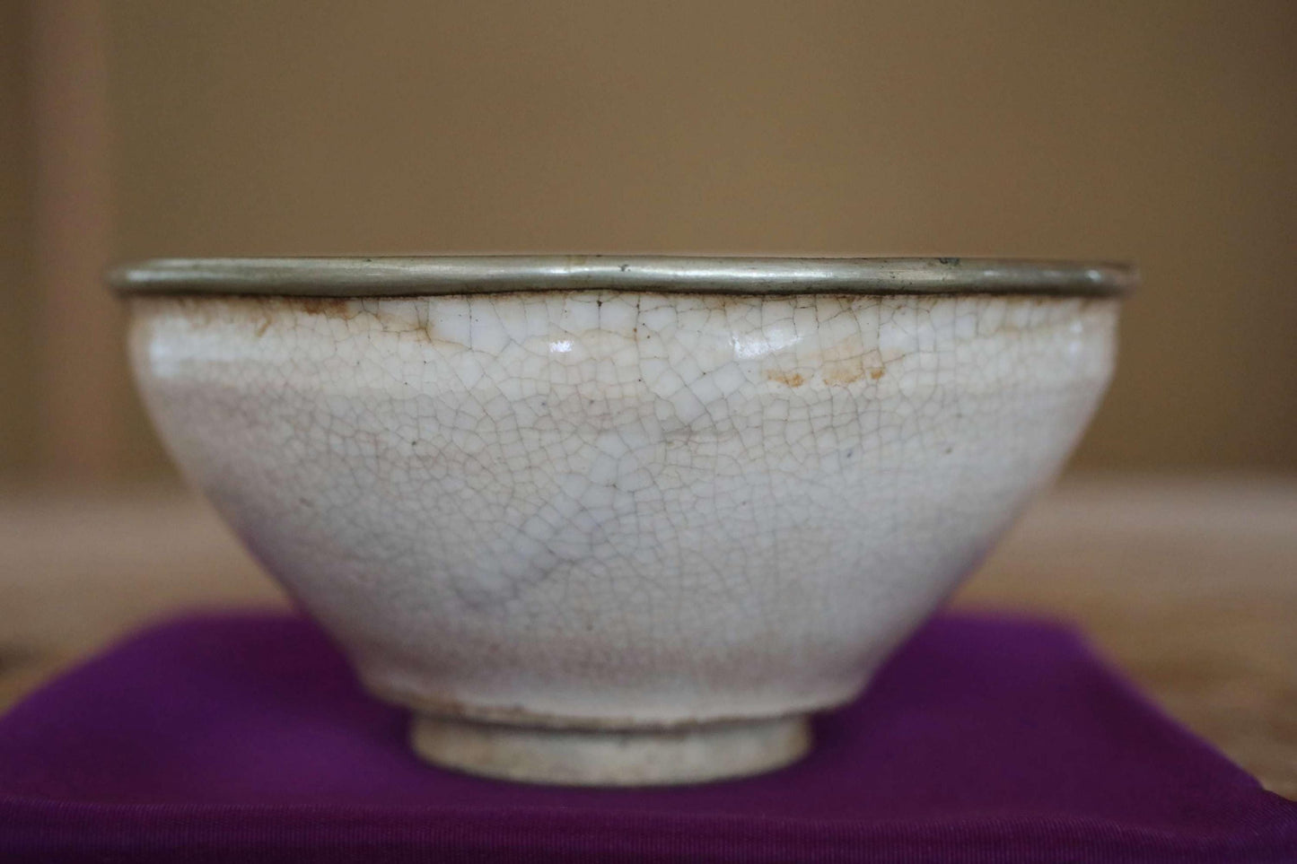 A white ceramic bowl with a textured surface sits on a purple cloth.