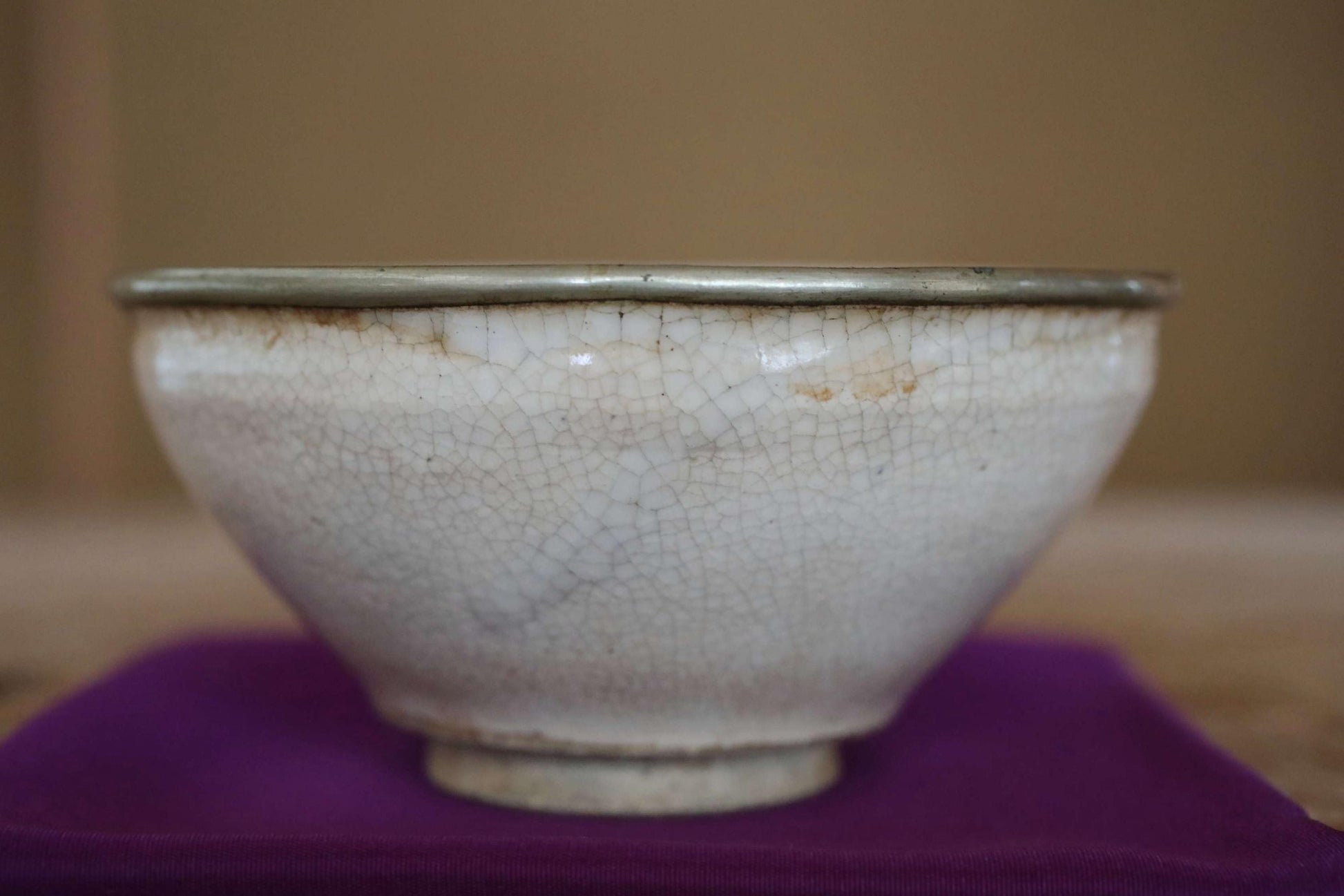A white ceramic bowl with a textured surface sits on a purple cloth.