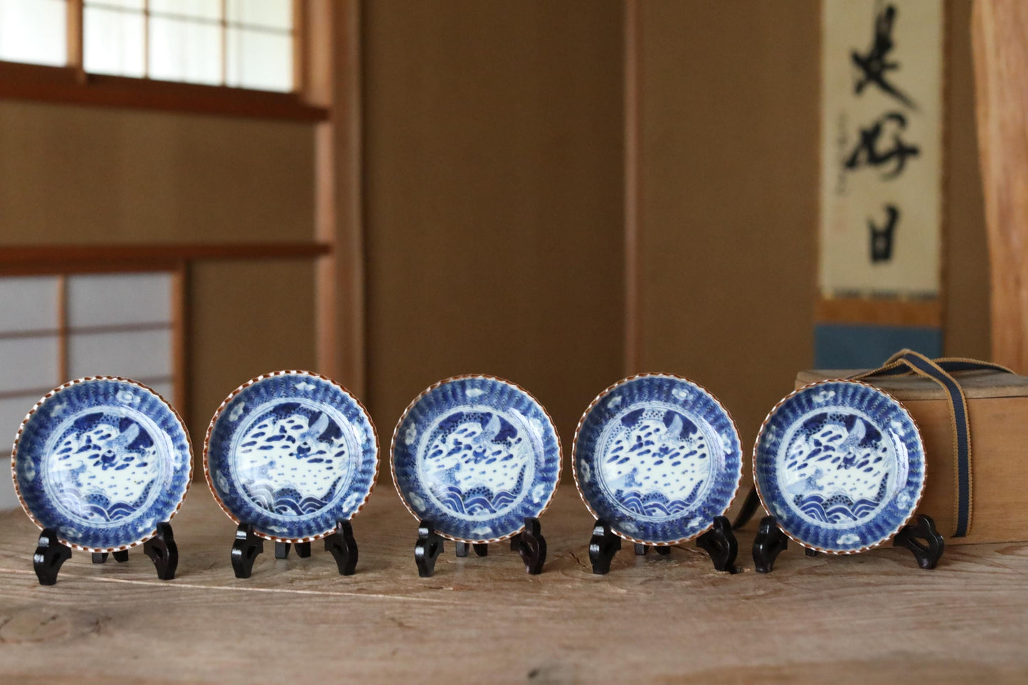 A row of five blue and white porcelain plates with intricate designs, displayed on a wooden surface.