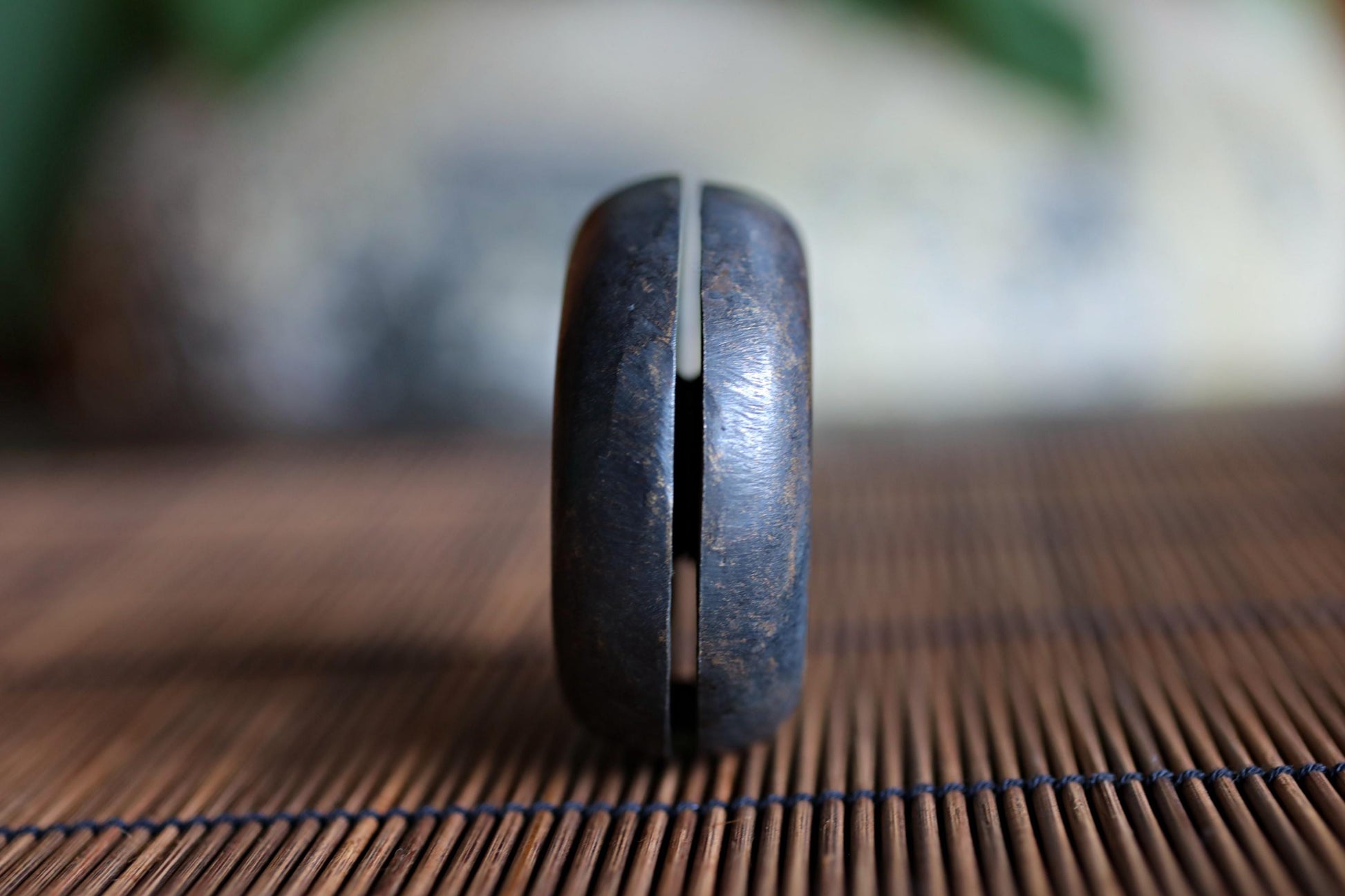 A close-up view of a metal object, possibly a tool or utensil, with a textured surface and a blurred background.