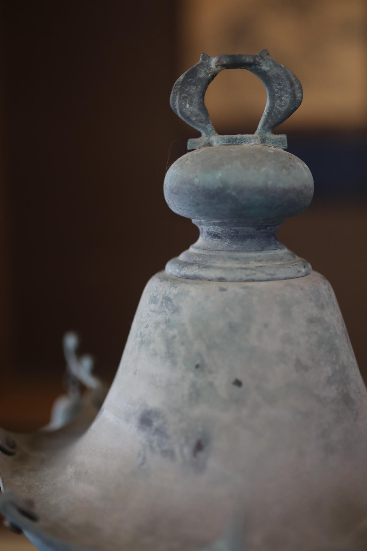 A close-up view of a metal object, possibly a piece of furniture or a decorative item, with a textured surface and a small hole or opening on the top.