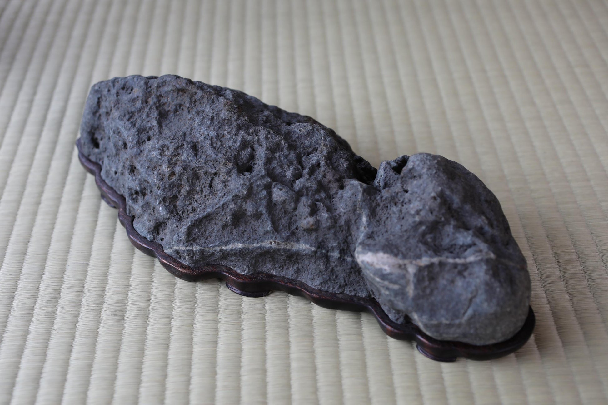 a large, gray rock sitting on a woven mat.