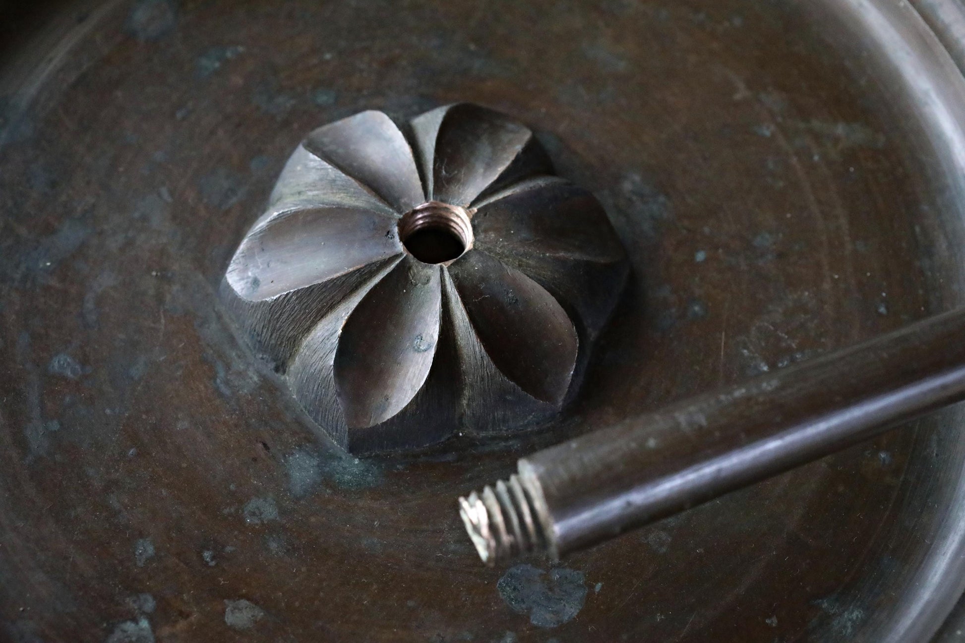 A close-up view of a metal object with a hole in the center, resting on a dark surface.
