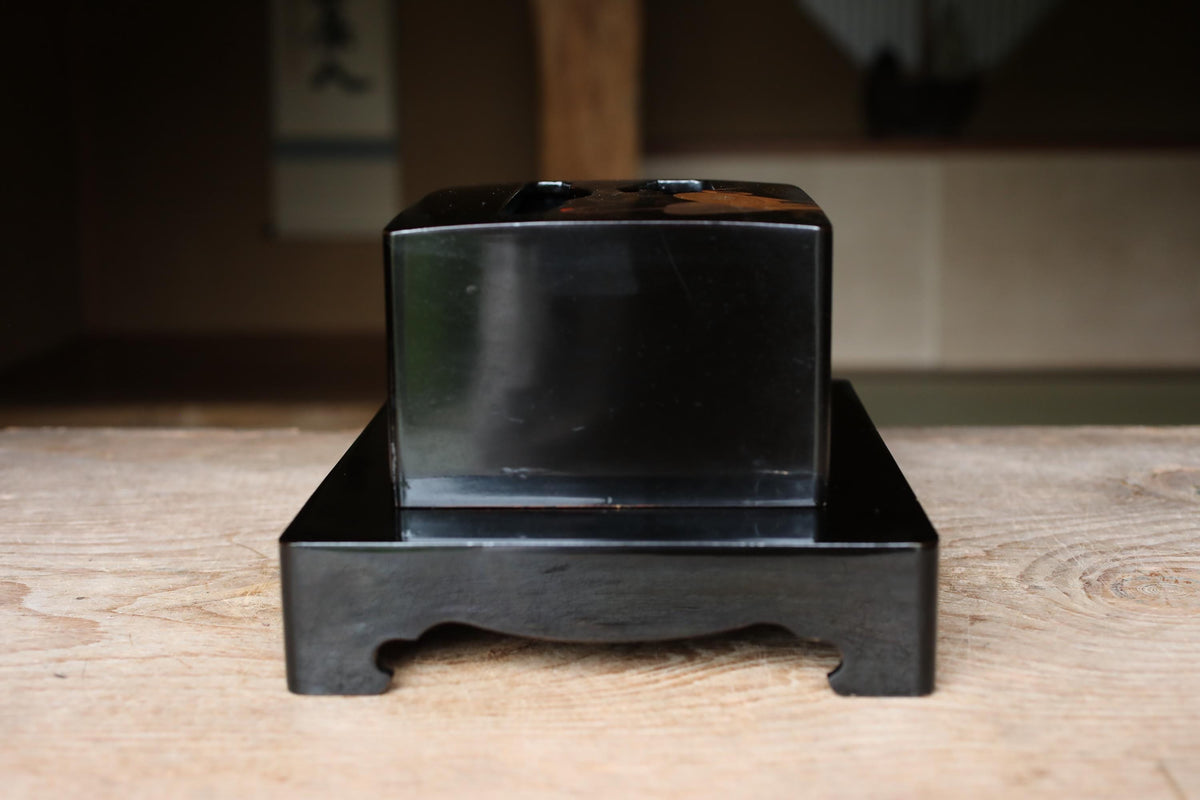 A black rectangular object is sitting on a wooden surface.