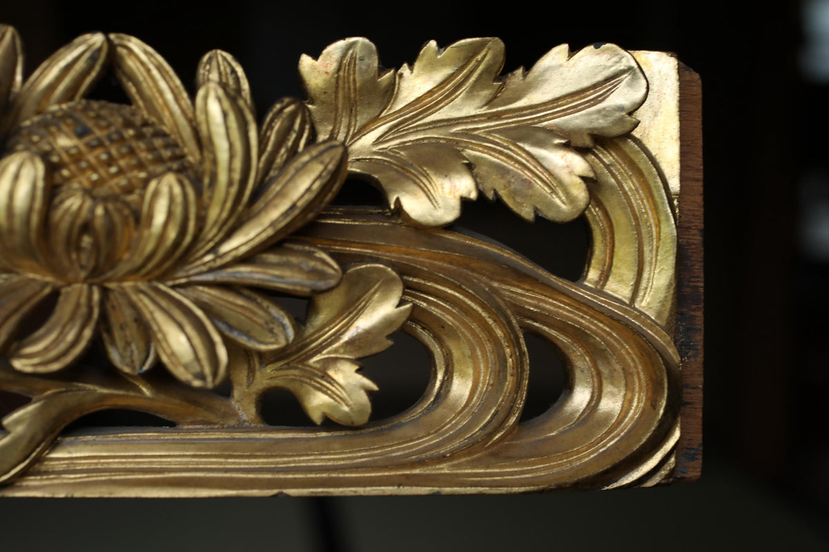 a close-up view of a decorative golden sculpture with intricate floral and leaf designs.