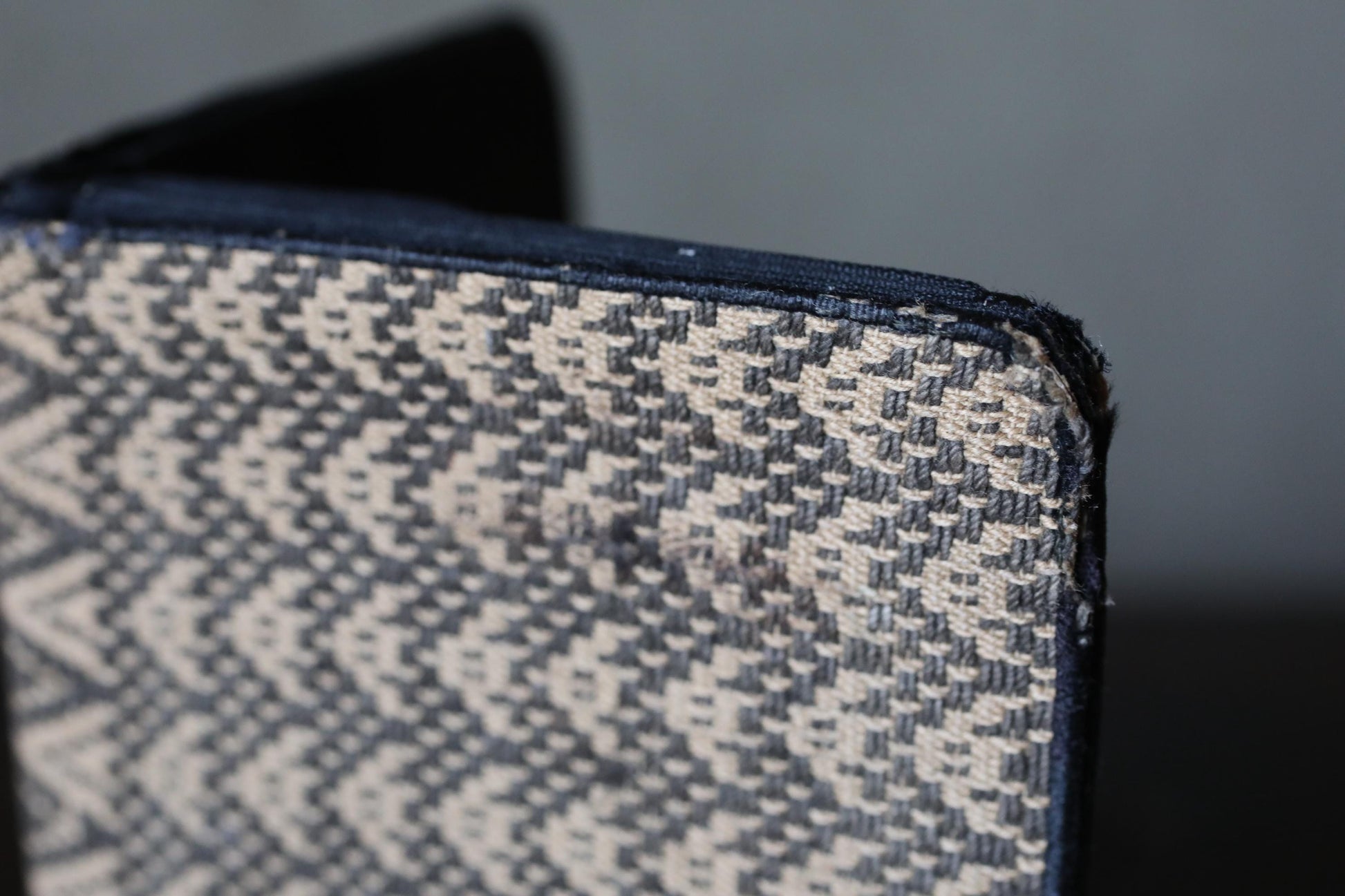 A close-up view of a textured fabric with a zigzag pattern, showing a small tear or damage on the edge.