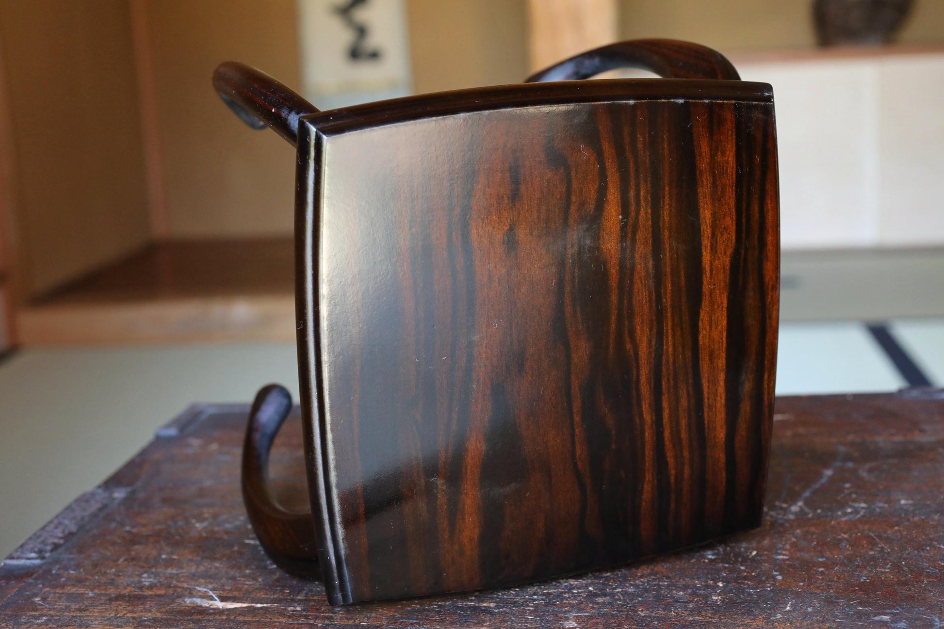 a wooden object with a dark finish, sitting on a wooden surface.