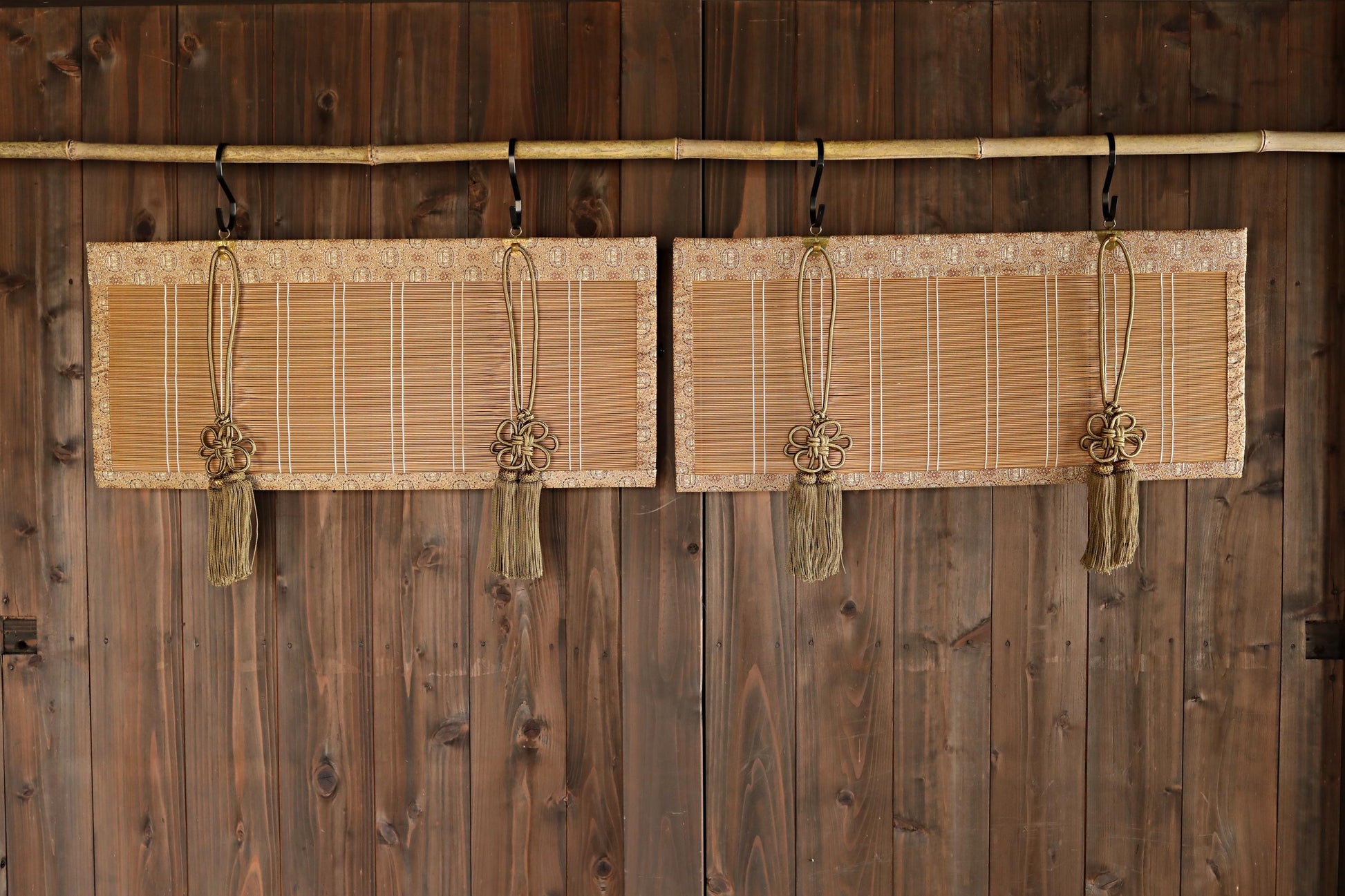 a pair of wooden blinds hanging on a wooden wall, each with a tassel hanging from the top.