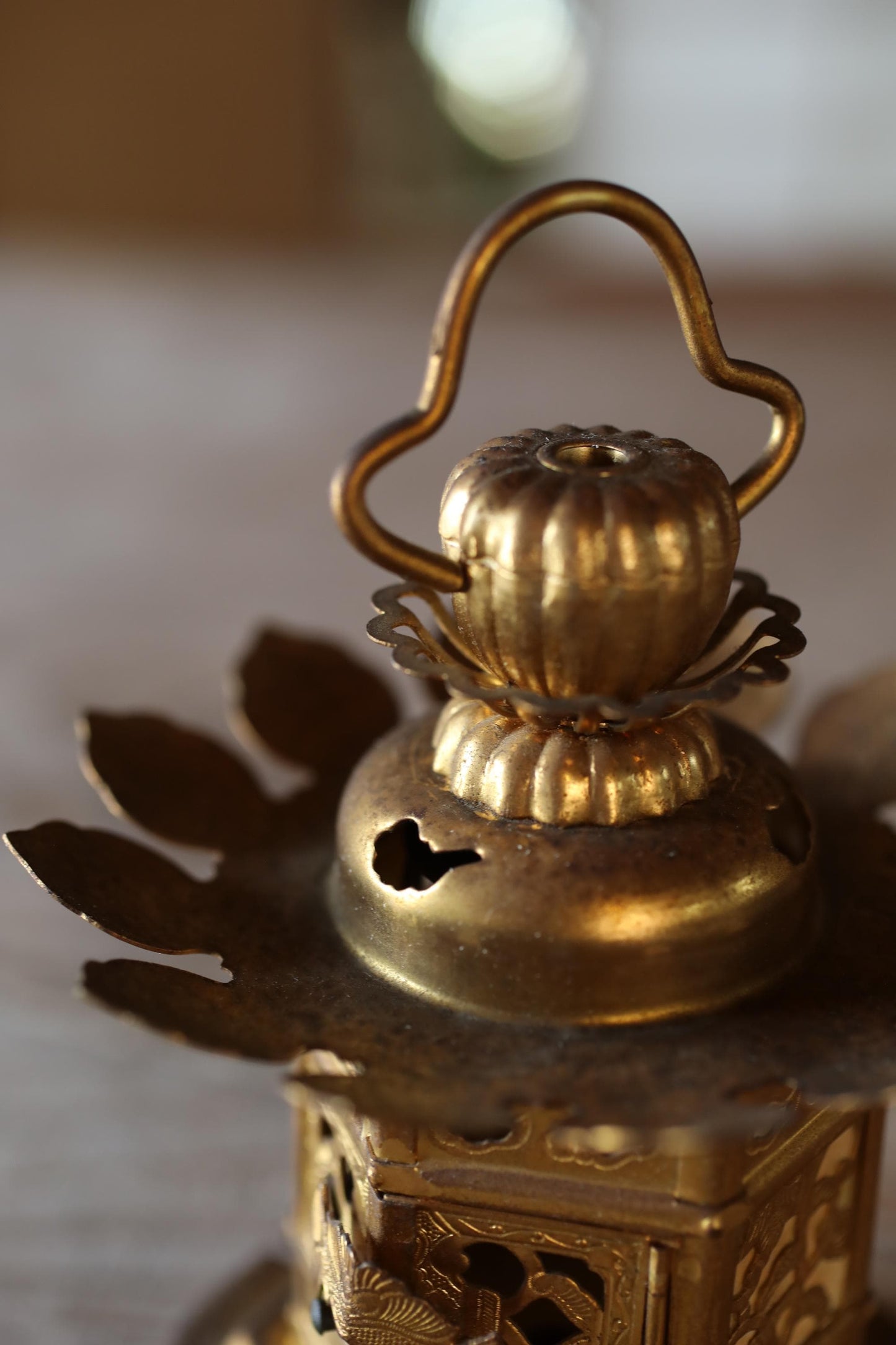 A close-up view of a decorative golden lantern with a handle and a spout, featuring intricate designs and patterns.
