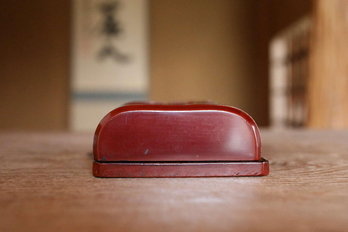 A red, oval-shaped object is sitting on a wooden surface.