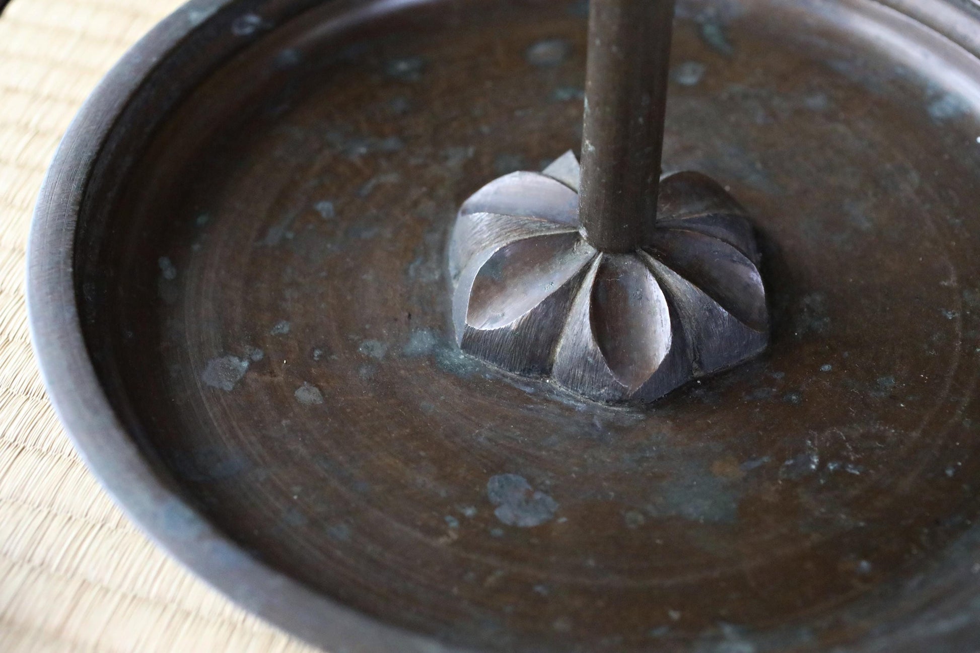 a close-up view of a metal object, possibly a piece of furniture or a decorative item, with a textured surface and a small, ornate base.