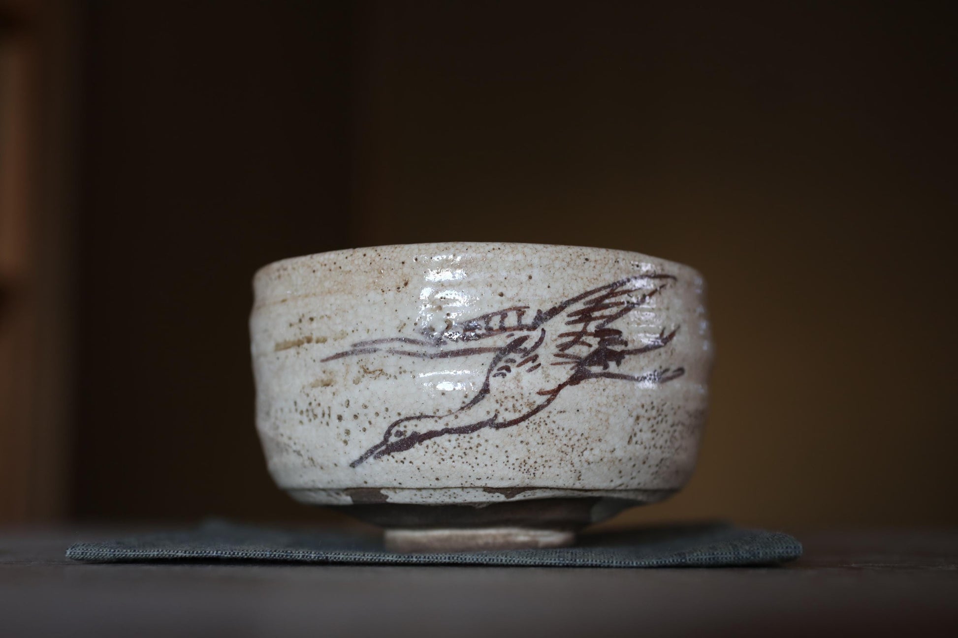 A ceramic bowl with a bird design on it, placed on a dark surface.