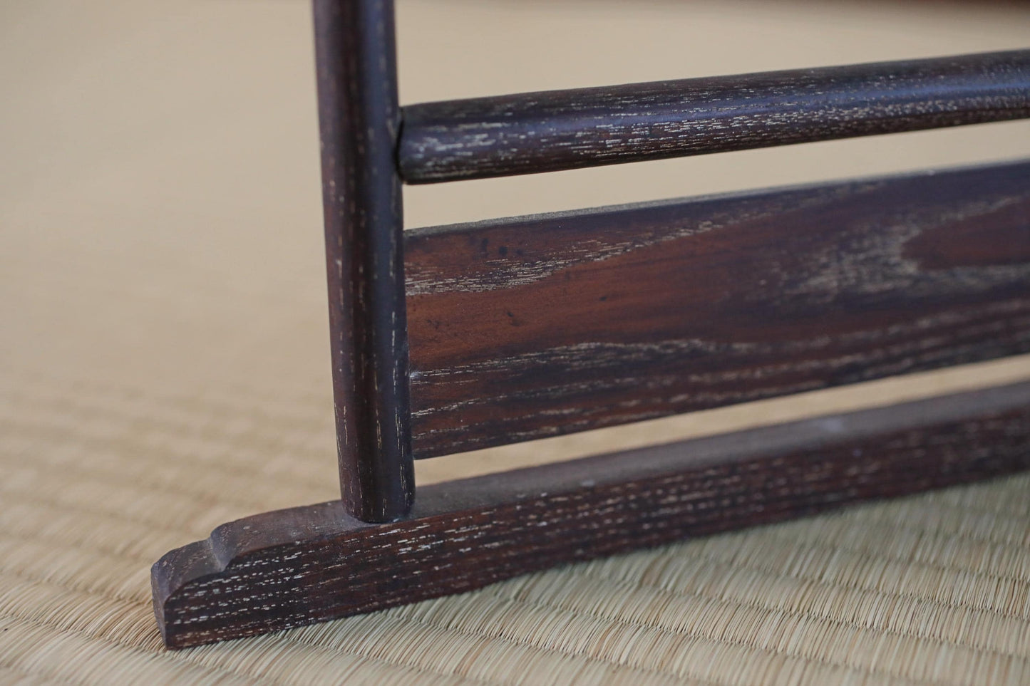 a close-up view of a wooden object, possibly a piece of furniture or a decorative item, with a textured surface and a dark brown color.