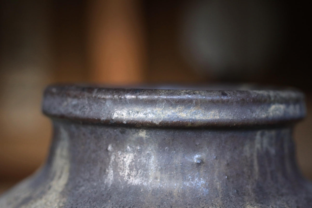 A close-up view of a metal object, possibly a piece of pottery or a sculpture, with a textured surface and a slightly rusted appearance.