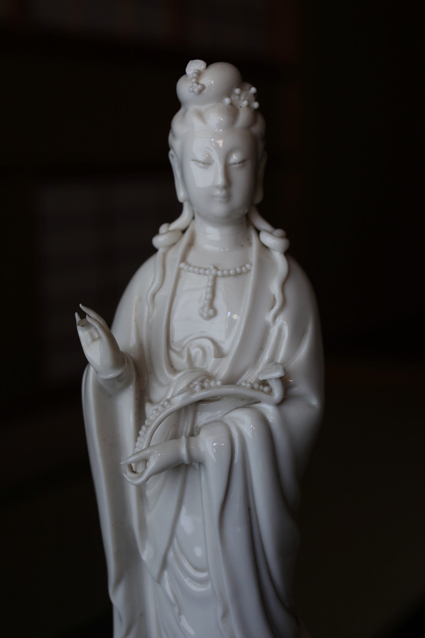 A white ceramic statue of a female deity, possibly a goddess or deity, with intricate details and a flowing robe.