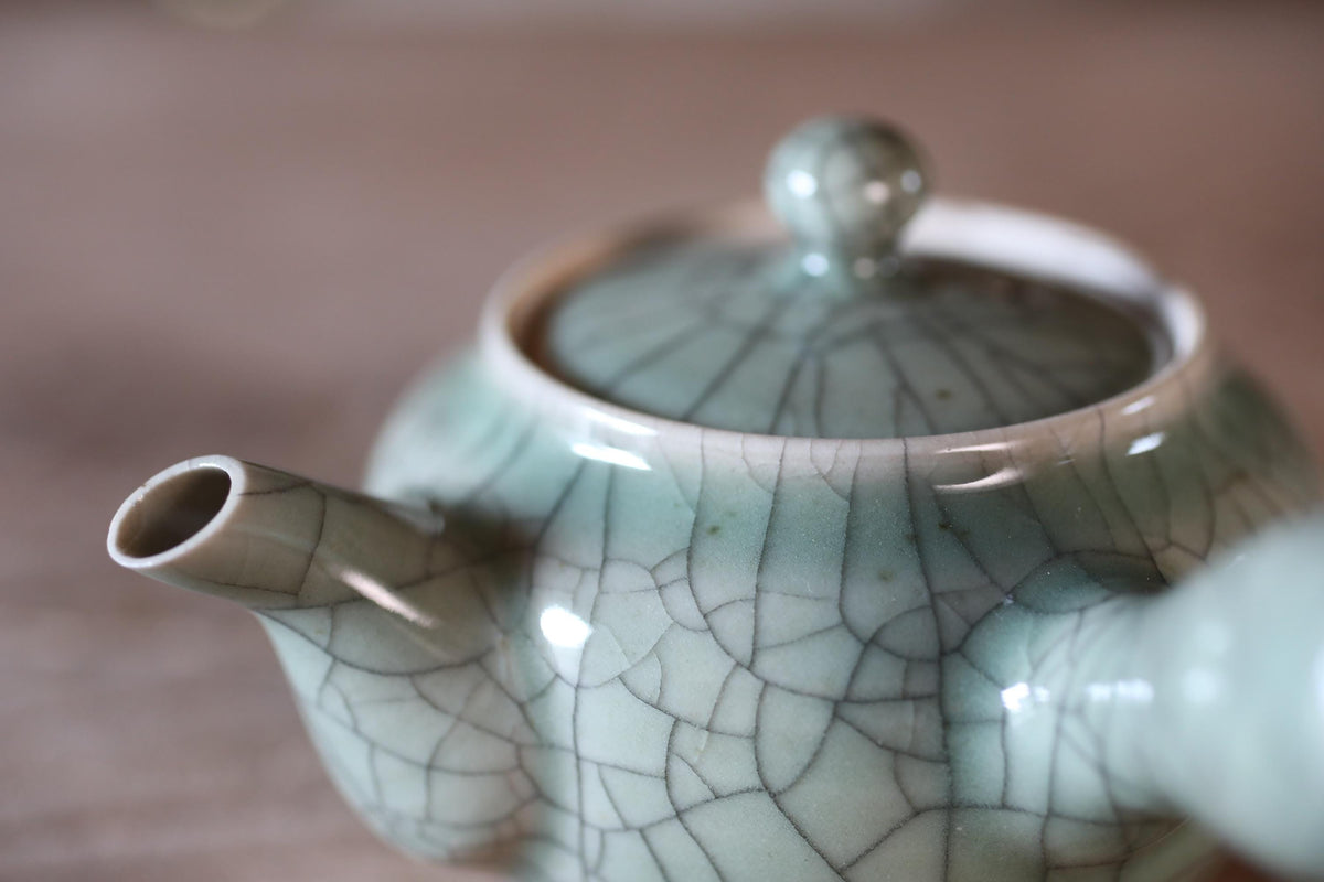 A close-up image of a ceramic teapot with a textured, cracked pattern in shades of blue and green.