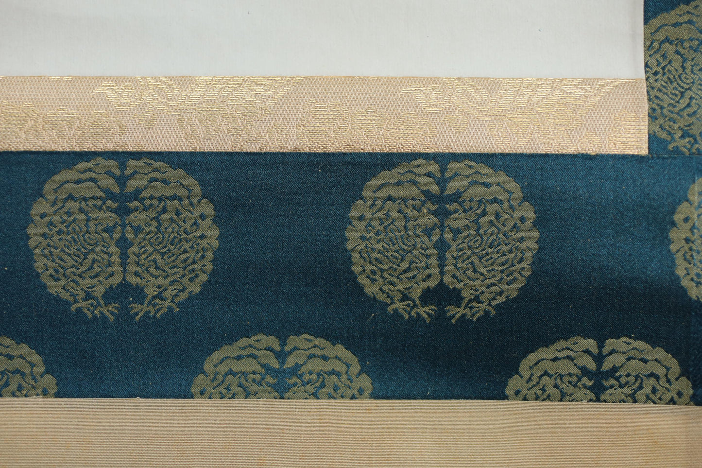 a close-up view of a fabric with a repeating pattern of gold peacock designs on a dark blue background.