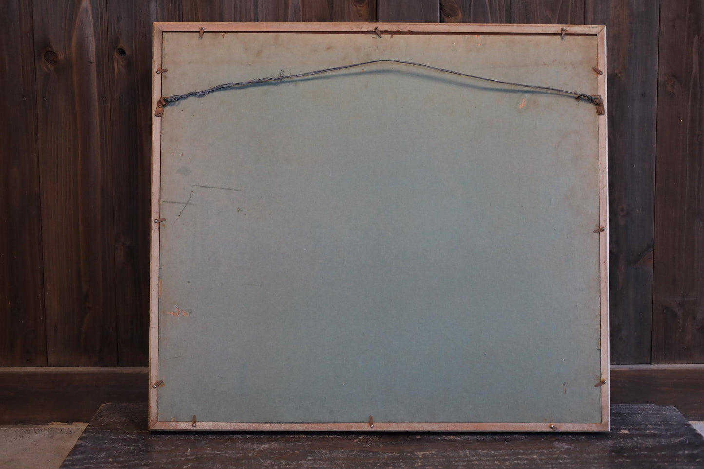 a wooden frame with a blank canvas inside, placed against a wooden wall.