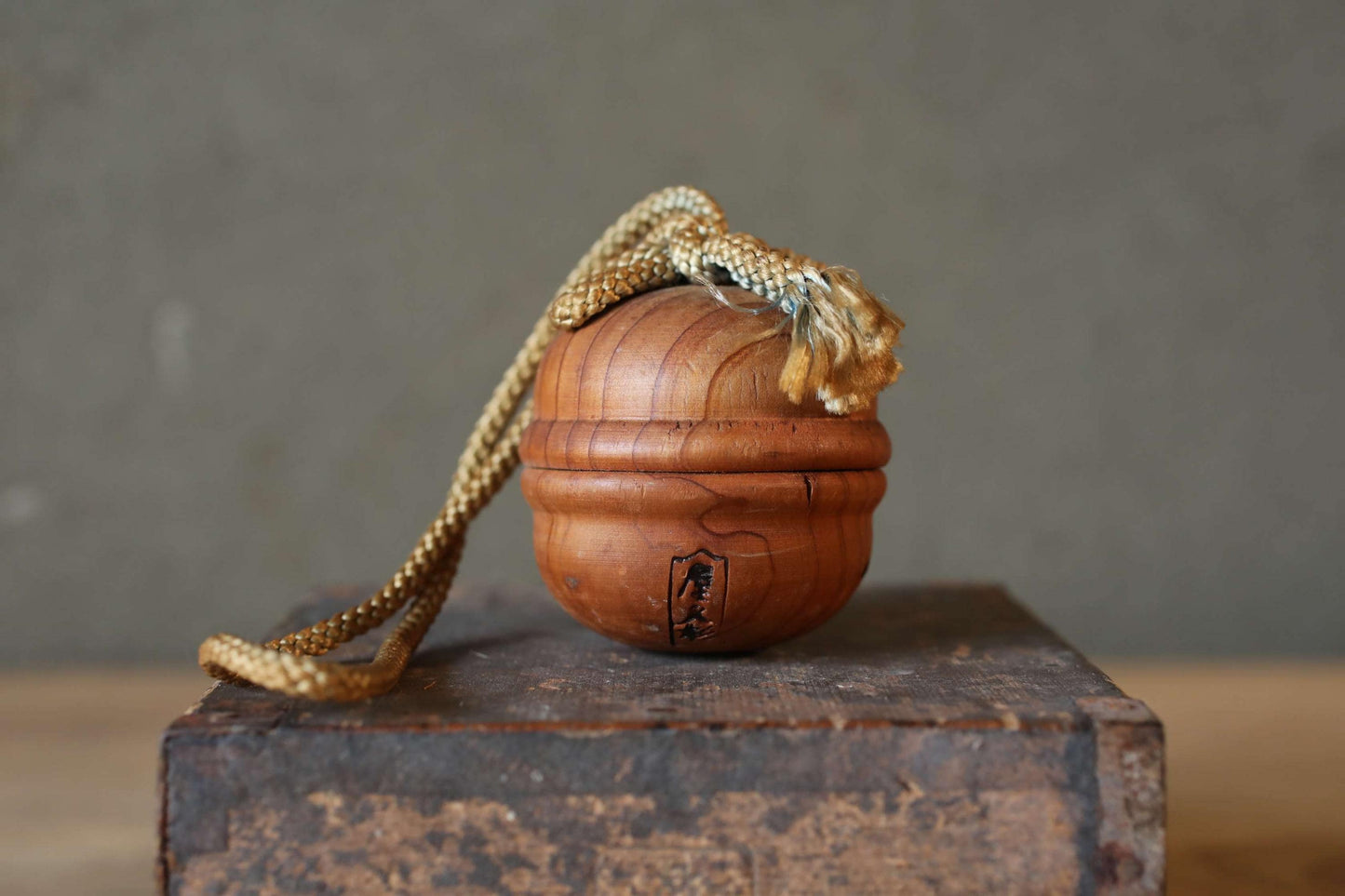 A wooden ball with a rope tied around it, sitting on a wooden surface.