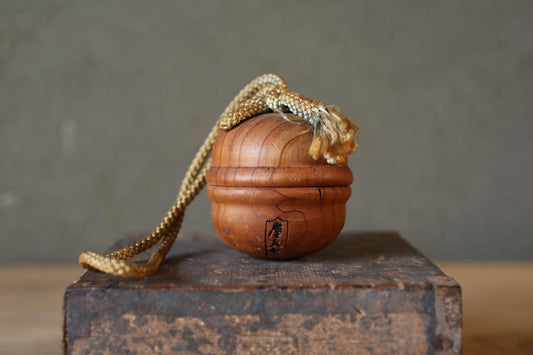 A wooden ball with a rope tied around it, sitting on a wooden surface.