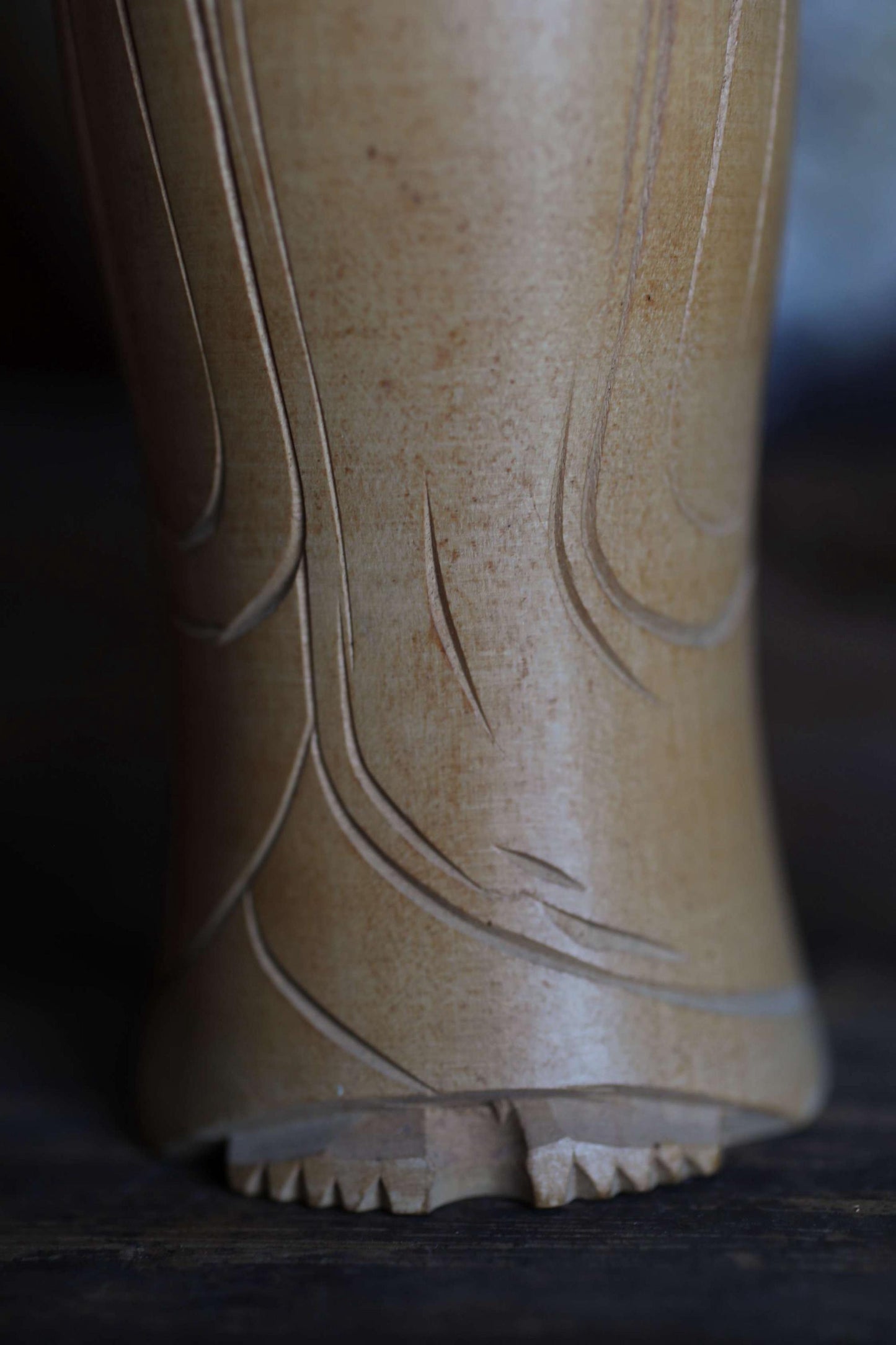 A close-up view of a wooden statue or sculpture, featuring intricate carved patterns and details.