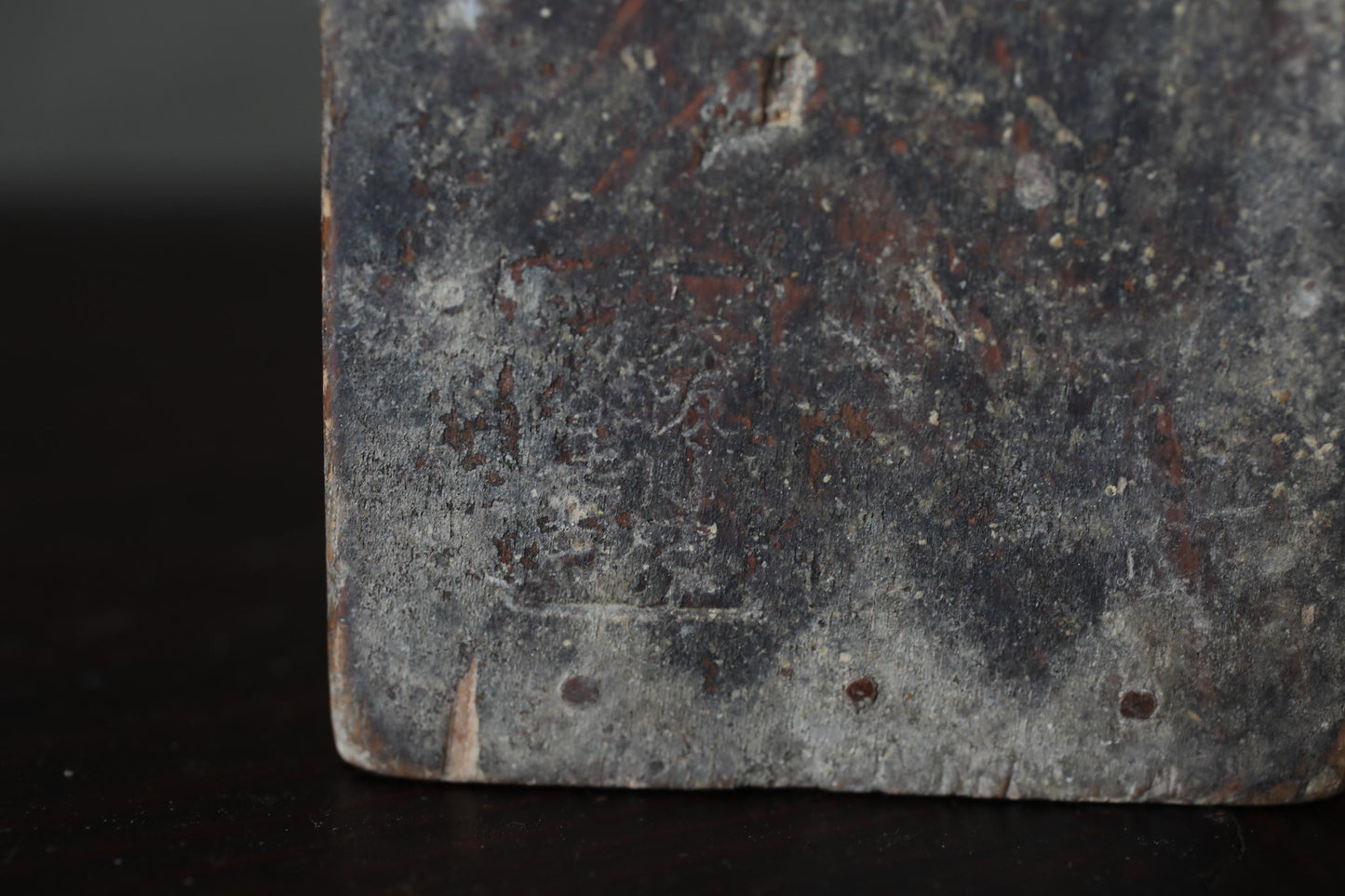 a close-up view of a weathered, dark-colored surface with some text or markings visible.