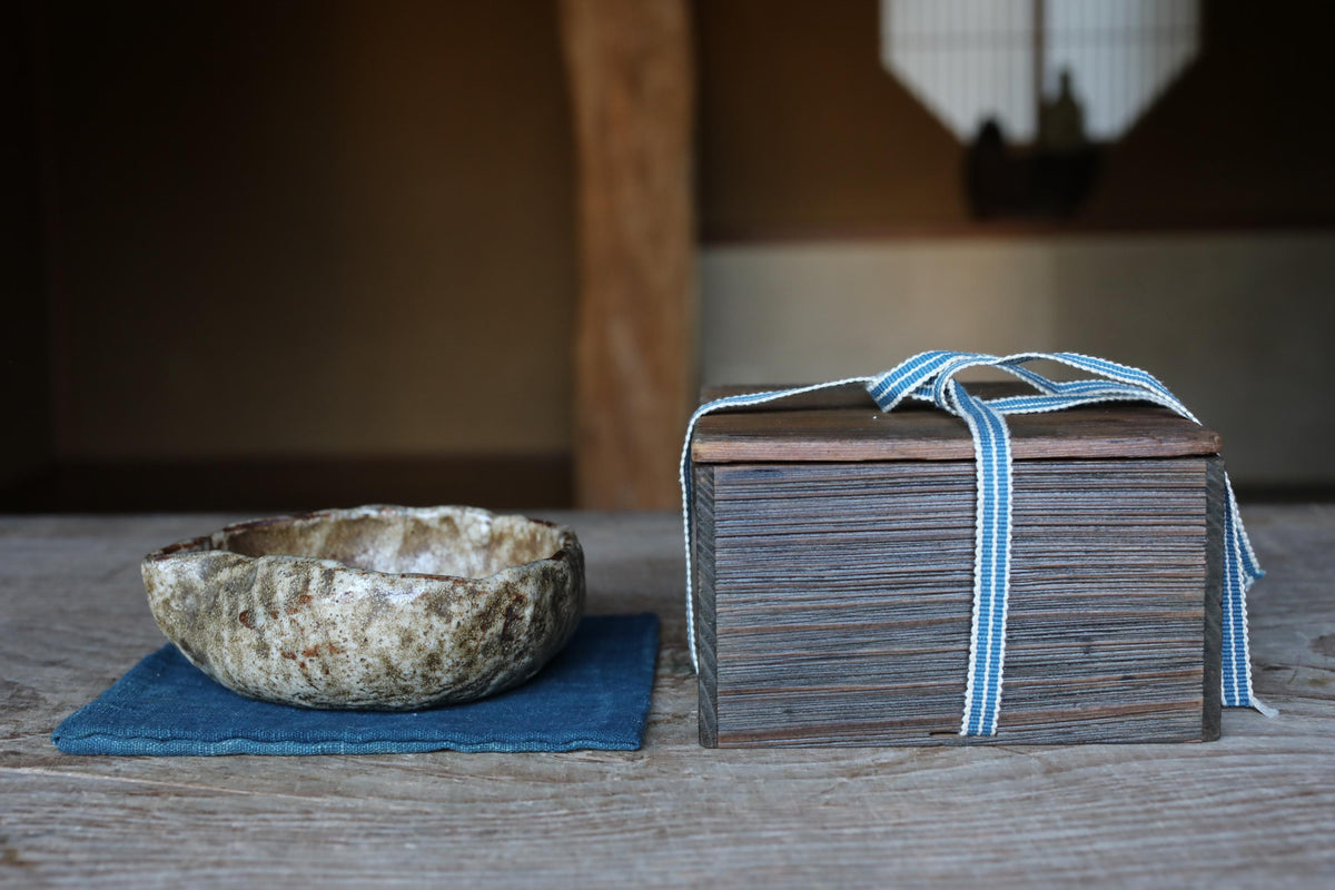 a wooden table with a small bowl and a stack of books tied together with a blue ribbon.