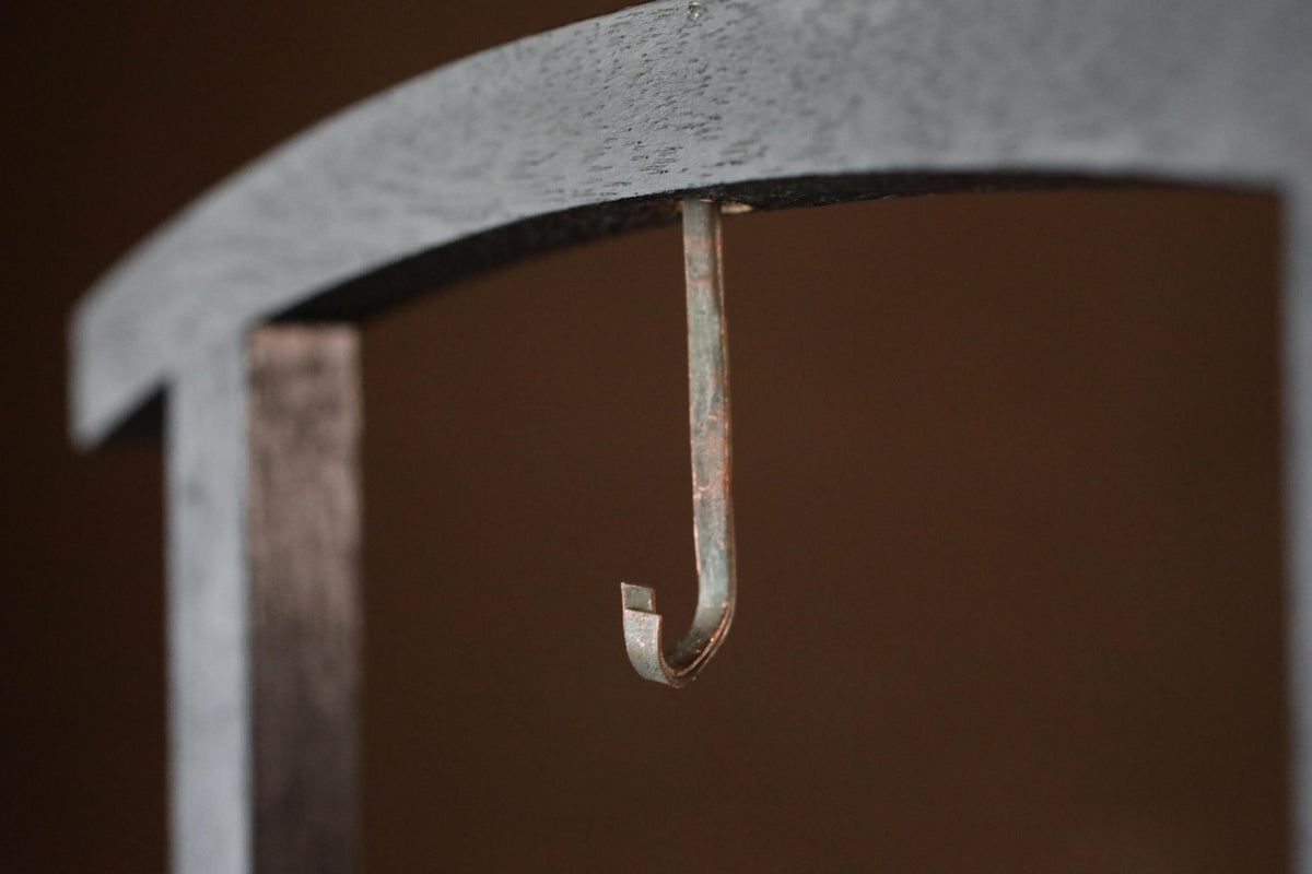 A close-up view of a metal hook or bracket attached to a curved wooden structure.