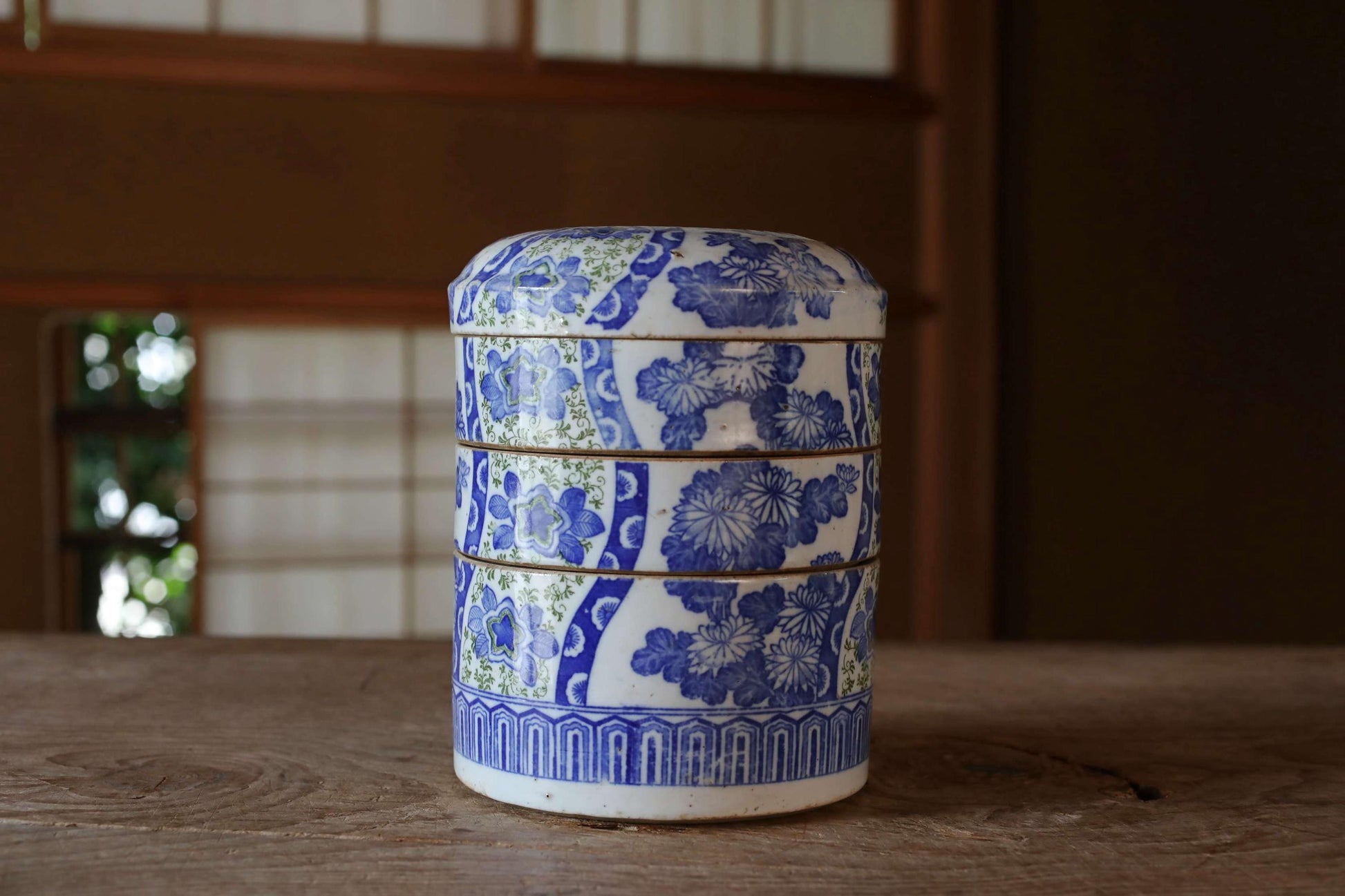 A decorative blue and white ceramic container with a floral pattern sits on a wooden surface.